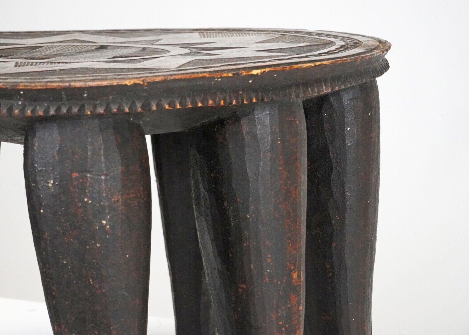 A superb example of a Nigerian Nupe stool. 
The circular top with star motif and geometric linear decoration. 
Deep chip carved rim on ten tapering legs. 
Made from one solid piece of hardwood it's heavy and robust. 
This particular piece has a