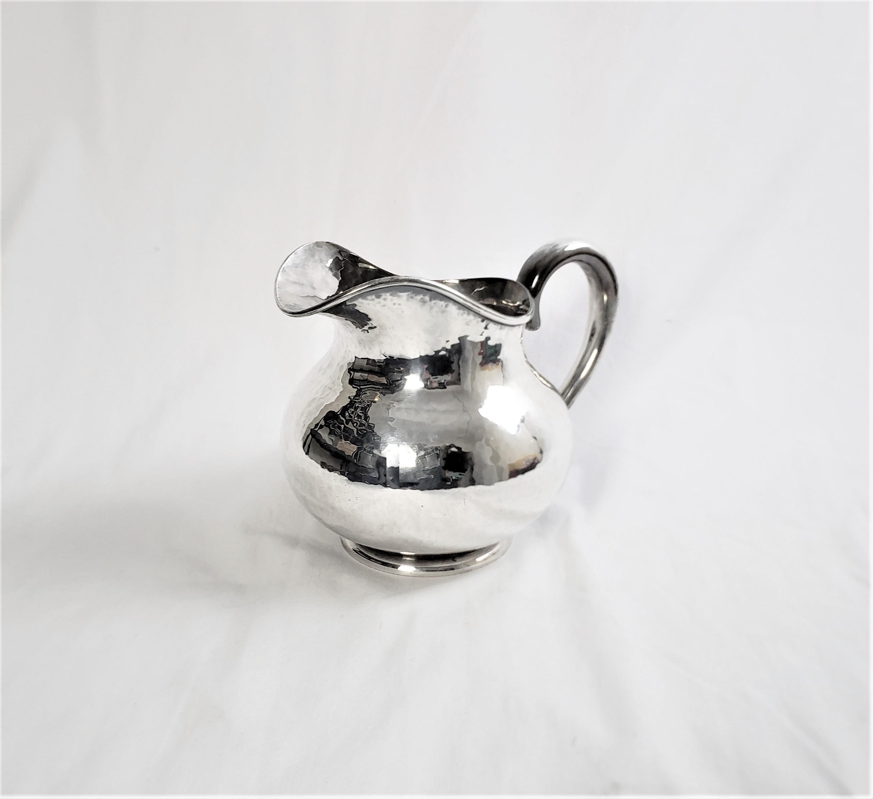 This small pitcher has no maker's marks, but presumed to have originated from the United States and date to approximately 1920 and done in the period Art Deco style. The pitcher is composed of hand hammered copper with a silver plated finish. The