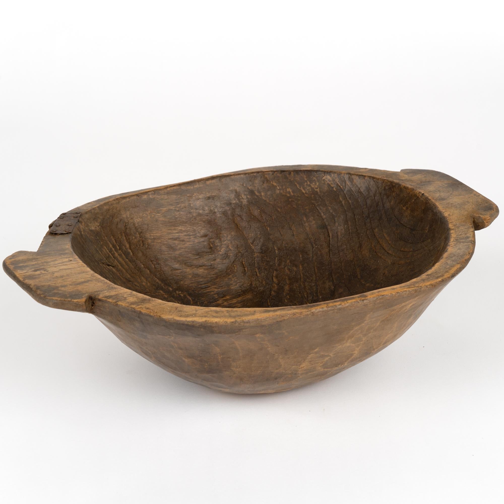 Antique hand-hewn wooden bowl with carved handles and typical old metal repair to strengthen bowl where crack began. Wonderful deep patina.
Old cracks, nicks, stains, distress are reflective of generations of use. 
Waxed and ready to use as