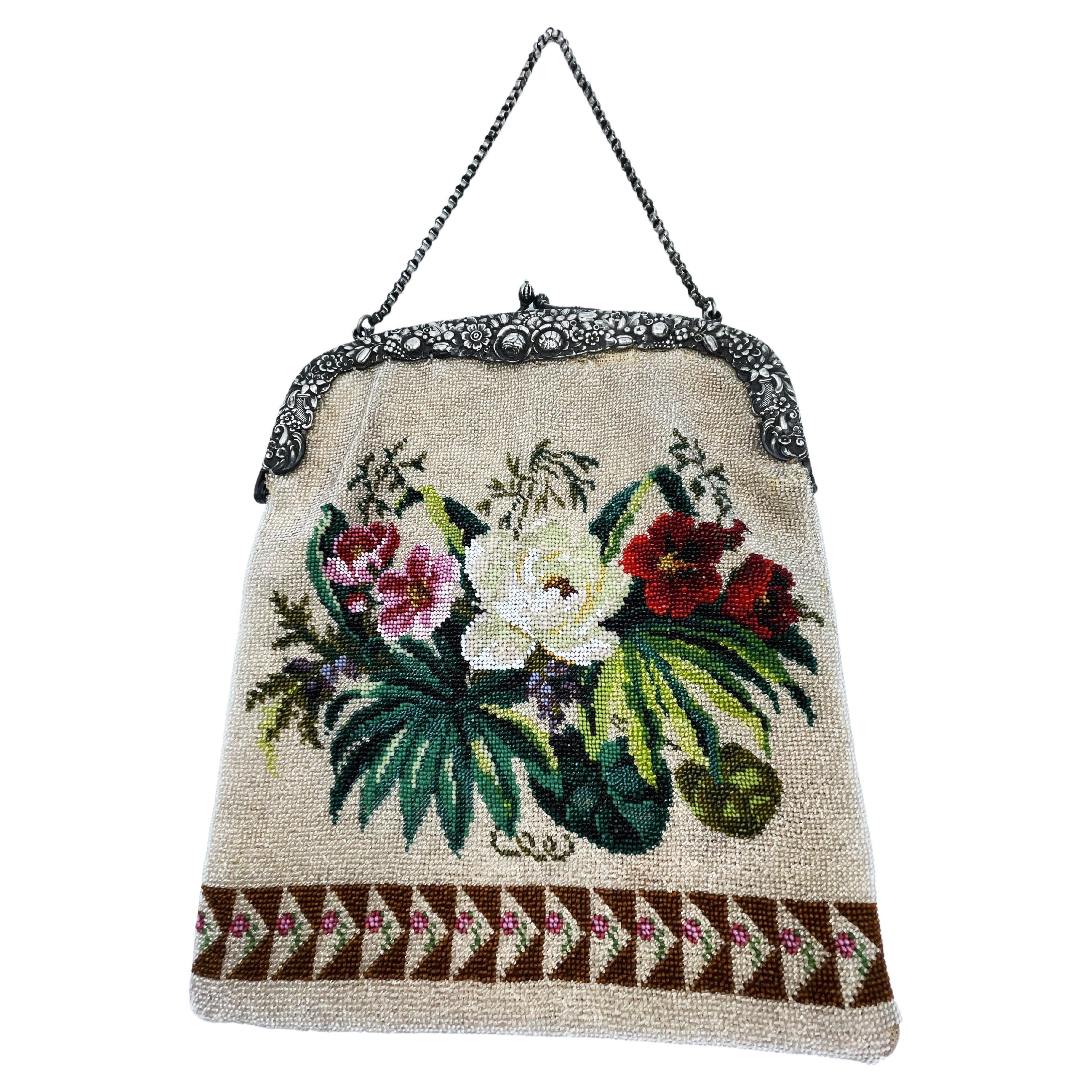 
The beaded bag has a silver handle in the shape of a double arch, which is designed with an adjuster made of stylized flower and leaf tendrils and has a pressure closure. A 38 cm long pea chain is attached to 2 eyelets on the side.
The flat, tall