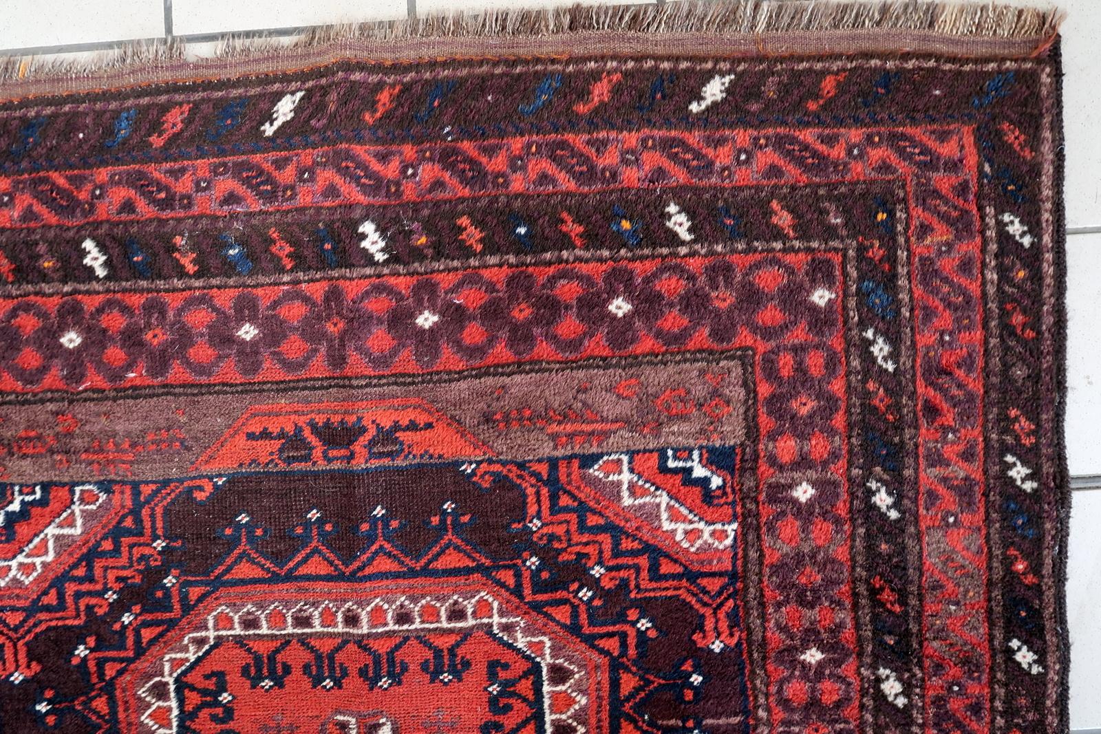 Un captivant et authentique tapis tribal Baluch antique, noué à la main en laine et originaire d'Afghanistan, datant des années 1920. Cette pièce illustre l'art distinct du peuple Baluch, des tisserands traditionnellement nomades connus pour leurs