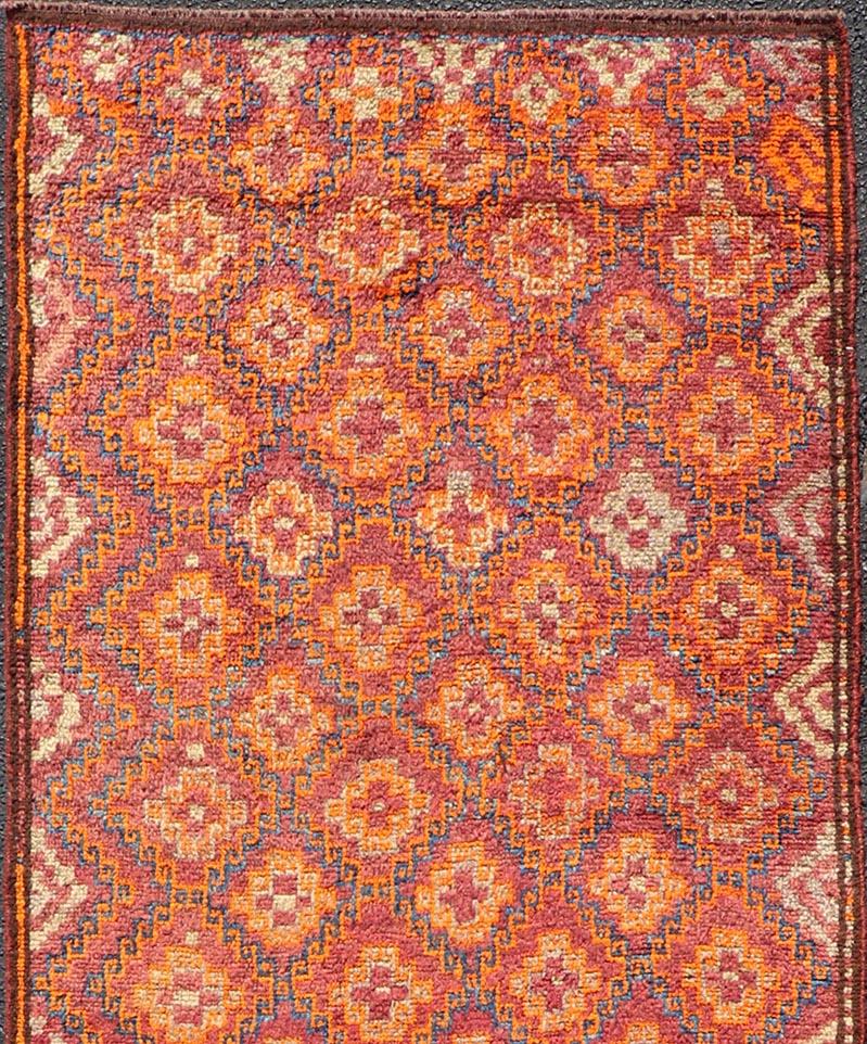 This Antique Baluch Runner has been hand-knotted and features an impressive all-over sub-geometric diamond design replete in multicolor. The rug is enclosed within a small complementary border; making it a perfect fit for a variety of classic,