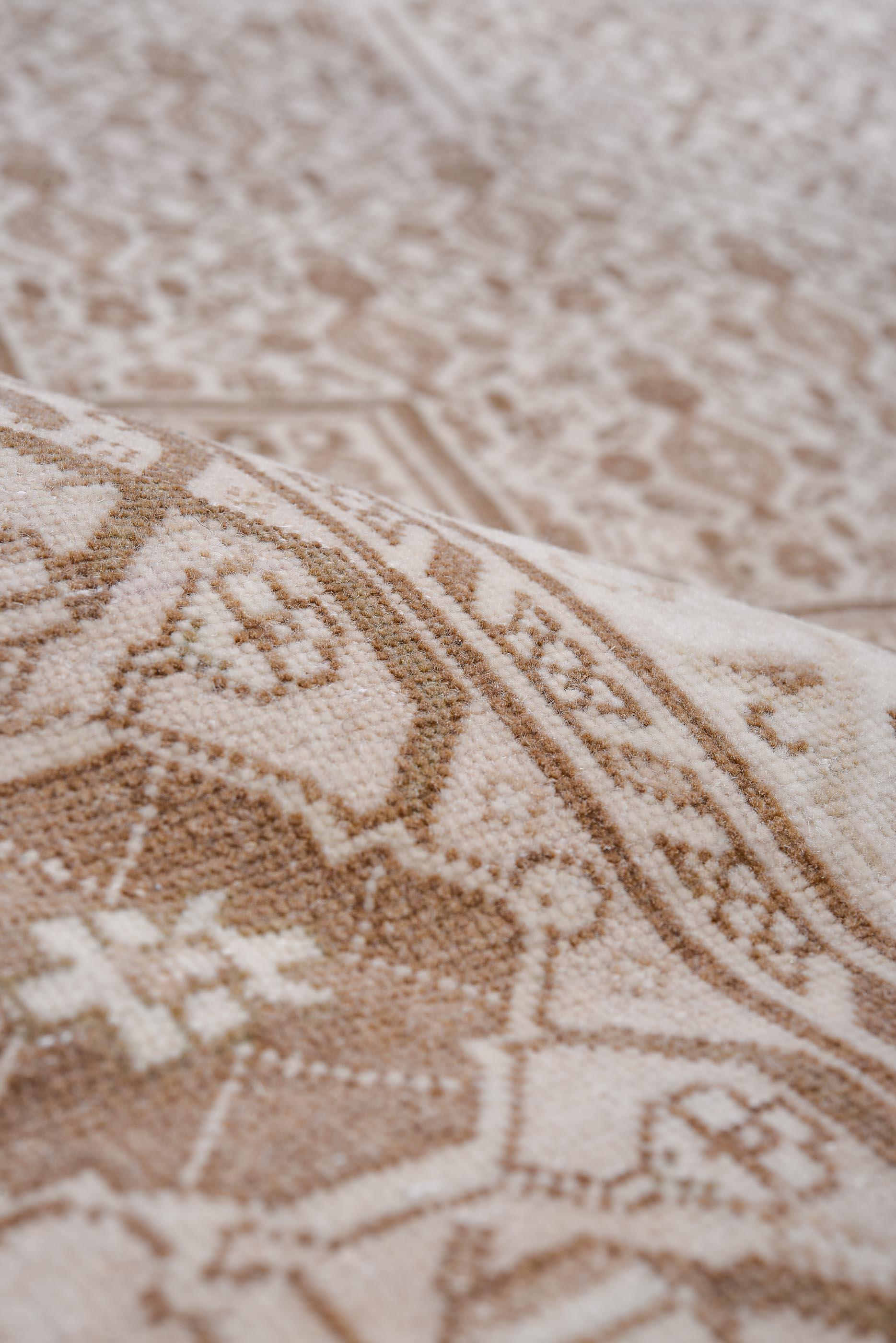 Dieser antike Bidjar-Teppich zeigt ein auffälliges geometrisches Medaillonmuster, das in einer raffinierten Farbpalette aus Taupe, Elfenbein und sanftem Braun sorgfältig von Hand gewebt wurde. Das detailreiche sechseckige Feld wird von