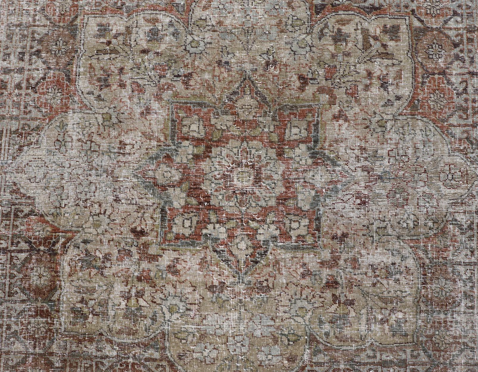 This antique distressed Persian Mahal rug has been hand-knotted in wool and features a large medallion design rendered in muted tones, a complementary, multi-tiered border encompasses the entirety of the piece; making it a marvelous fit for a wide