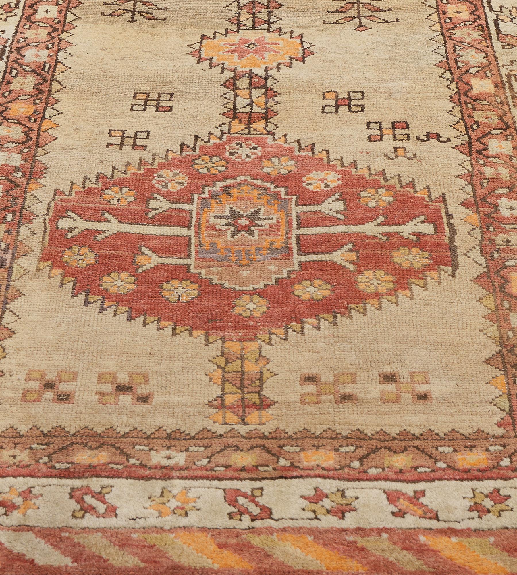 This antique Serab runner has a shaded camel-brown field scattered with floral stems and angular flowerheads around a central column of three linked terracotta-red and camel-brown serrated lozenges each containing a central floral lozenge surrounded