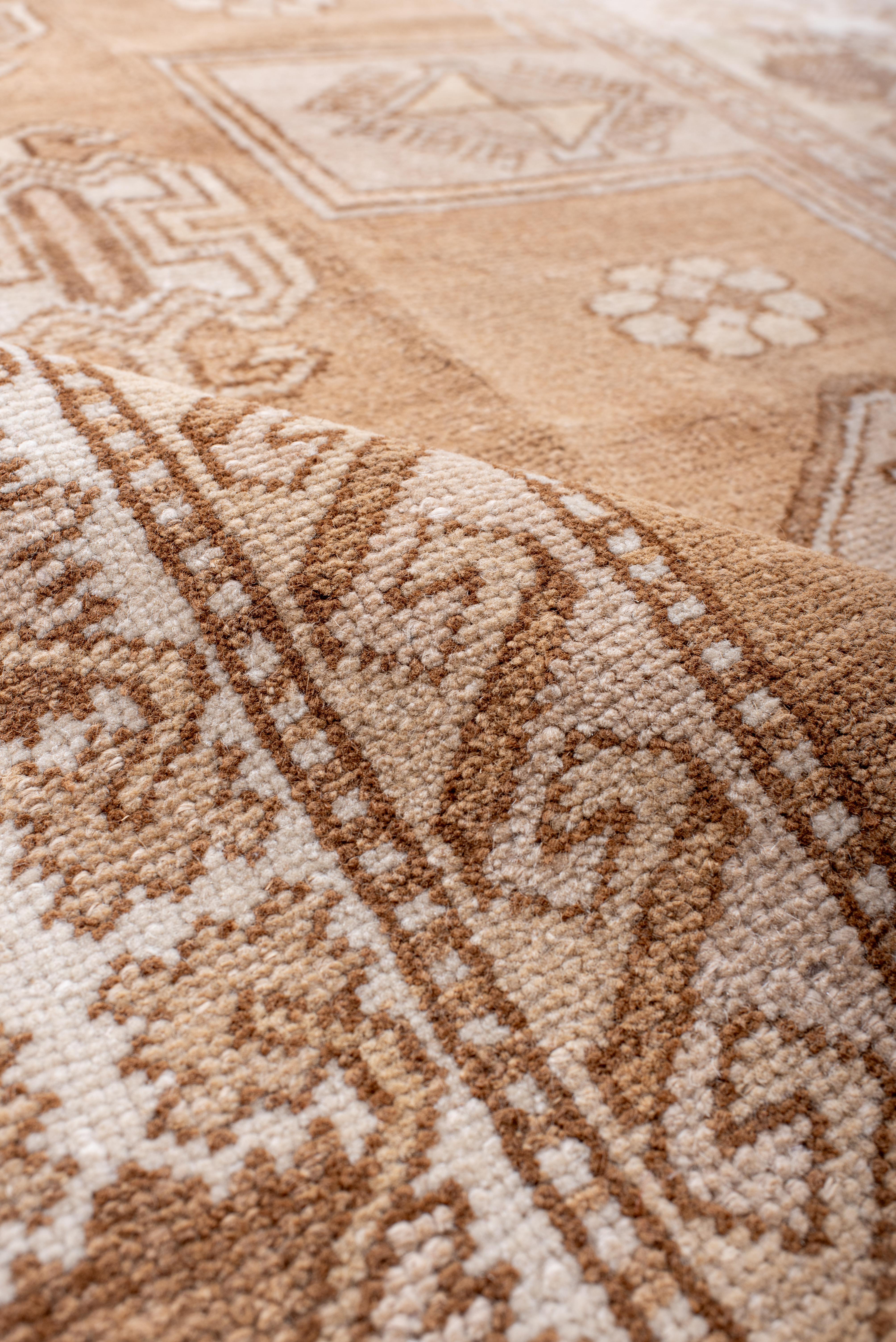 Dieser antike Kars-Teppich zeichnet sich durch ein auffälliges geometrisches Stammesmuster aus, das in einer warmen Palette aus sandfarbenem Beige, zartem Elfenbein und subtilen Akzenten in gedämpftem Blau gewebt ist. Die strukturierte Komposition