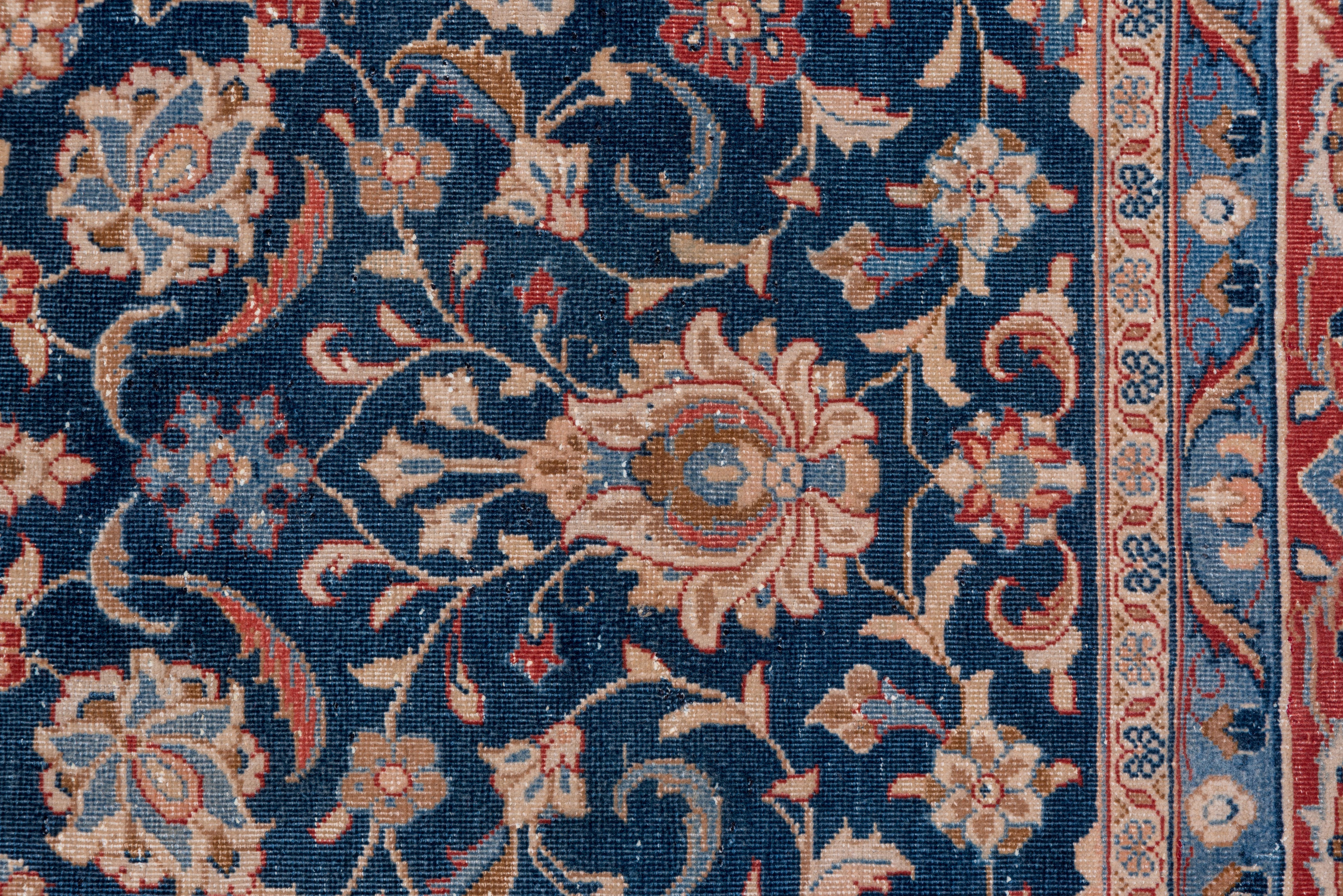 Dieser antike Kashan-Teppich zeigt exquisite persische Handwerkskunst mit einem tief mitternachtsblauen Feld, das mit einem komplizierten zentralen Medaillonmuster verziert ist, das von zarten Blumen- und Rankenmotiven in satten Karminrot-,