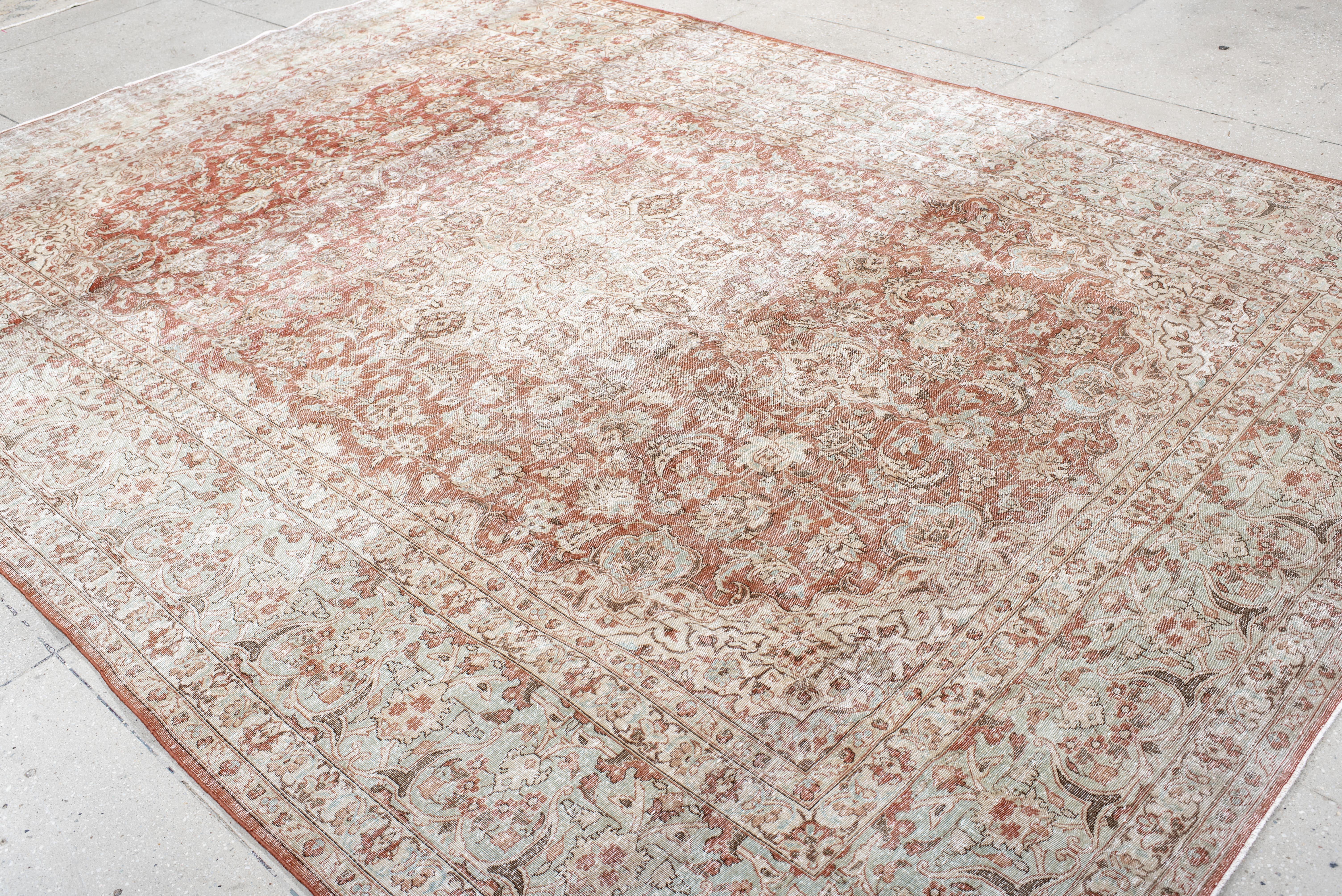This antique Kashan rug features a beautifully faded medallion design with an intricate floral pattern, woven in a warm palette of soft rust, ivory, and muted beige. The elegant balance of detailed arabesques and vine motifs creates a sense of