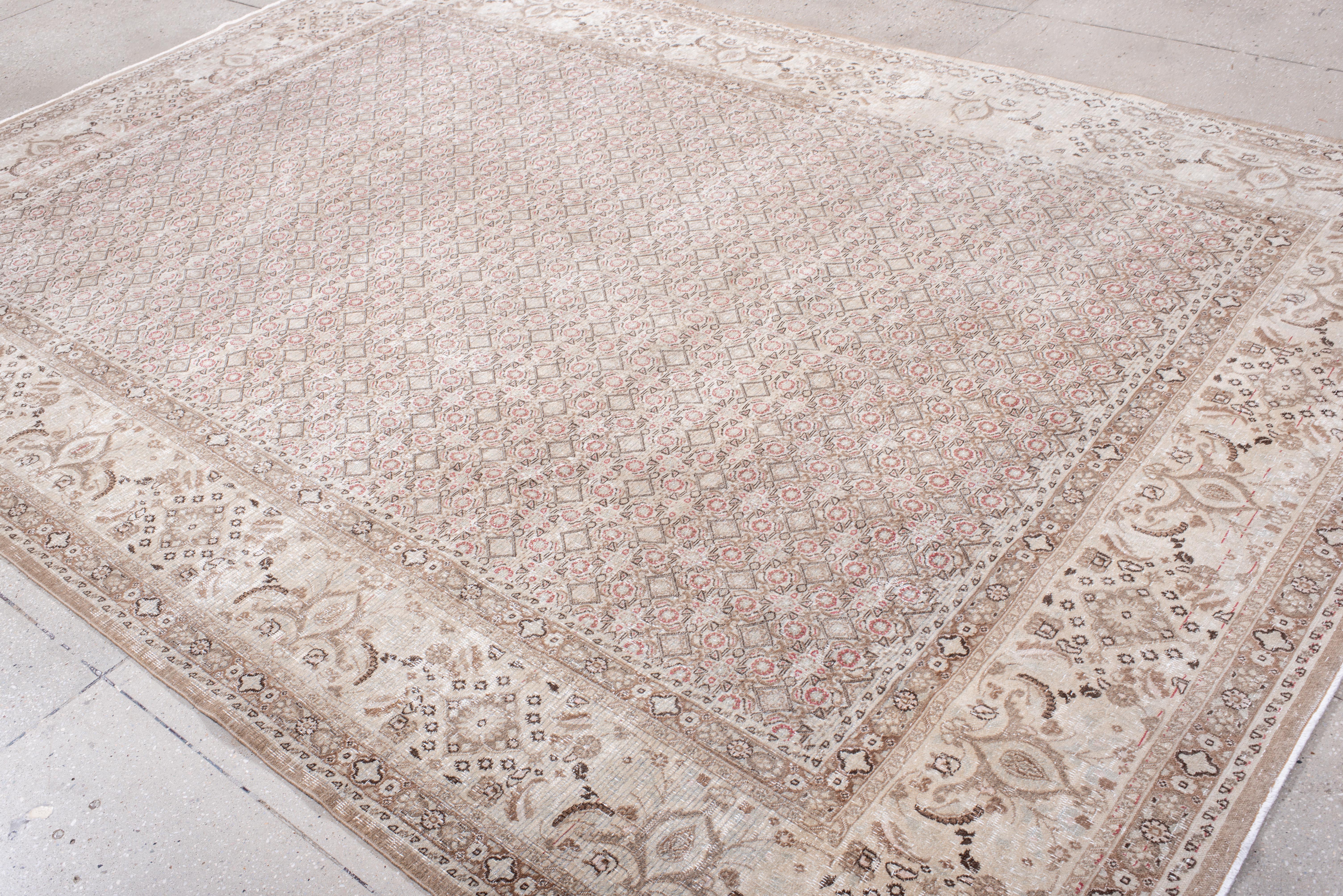 Dieser antike Khorassan-Teppich zeigt ein kompliziertes Gittermuster, das mit Präzision in einer gedämpften Farbpalette aus sanftem Elfenbein, Taupe und einem Hauch von verblasstem Rot gewebt wurde. Die zarten floralen und geometrischen Motive