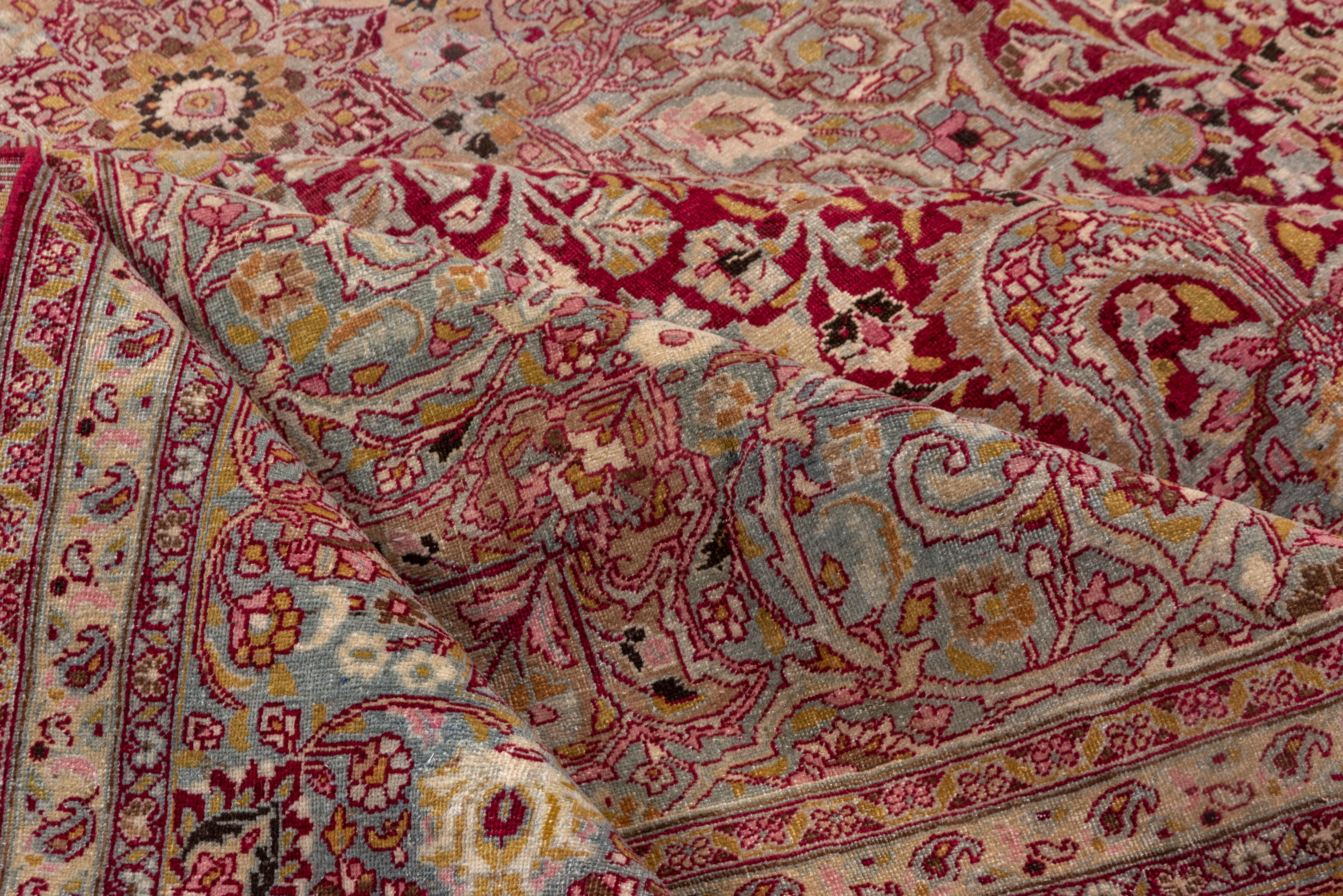 This antique Meshed rug showcases an opulent Persian floral design, featuring a striking deep crimson field adorned with intricate ivory, gold, and soft gray floral motifs. The richly decorated central medallion and ornate corner spandrels enhance