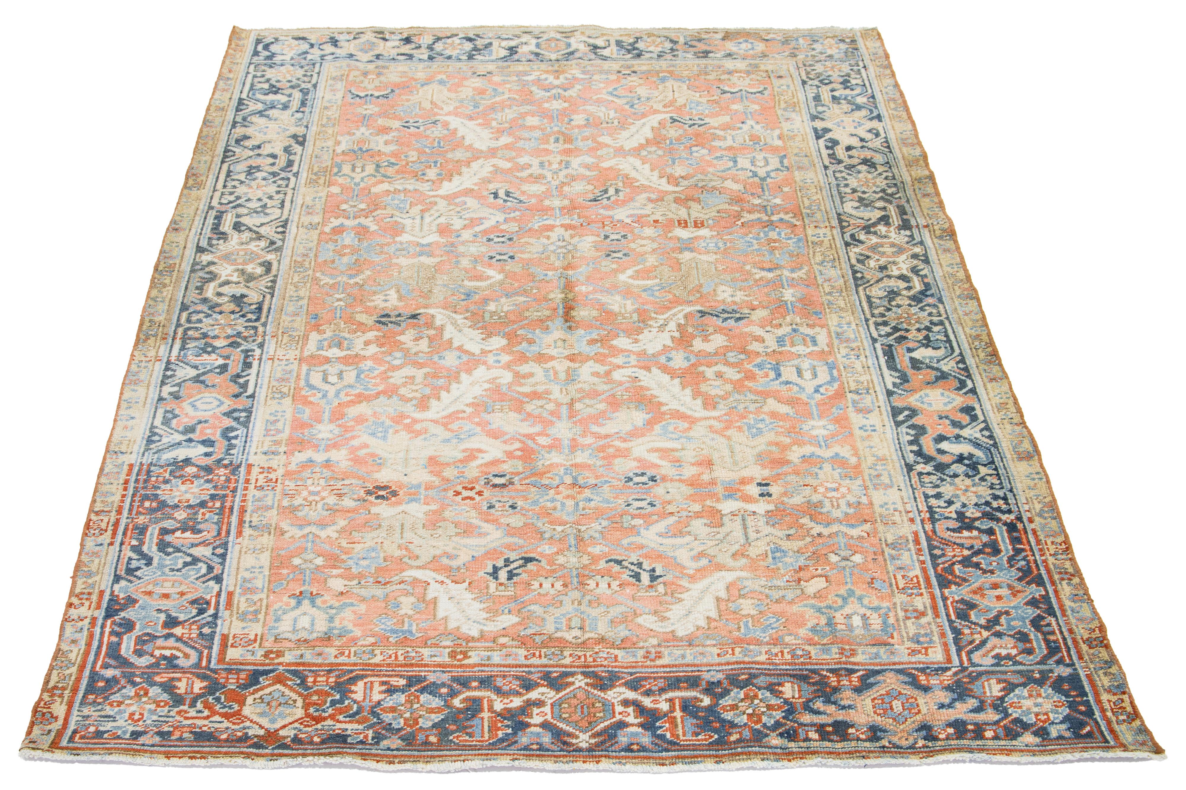 An antique Persian Heriz wool rug features a blue, beige, and brown pattern on a peach background.

This rug measures 6'9' x 9'4
