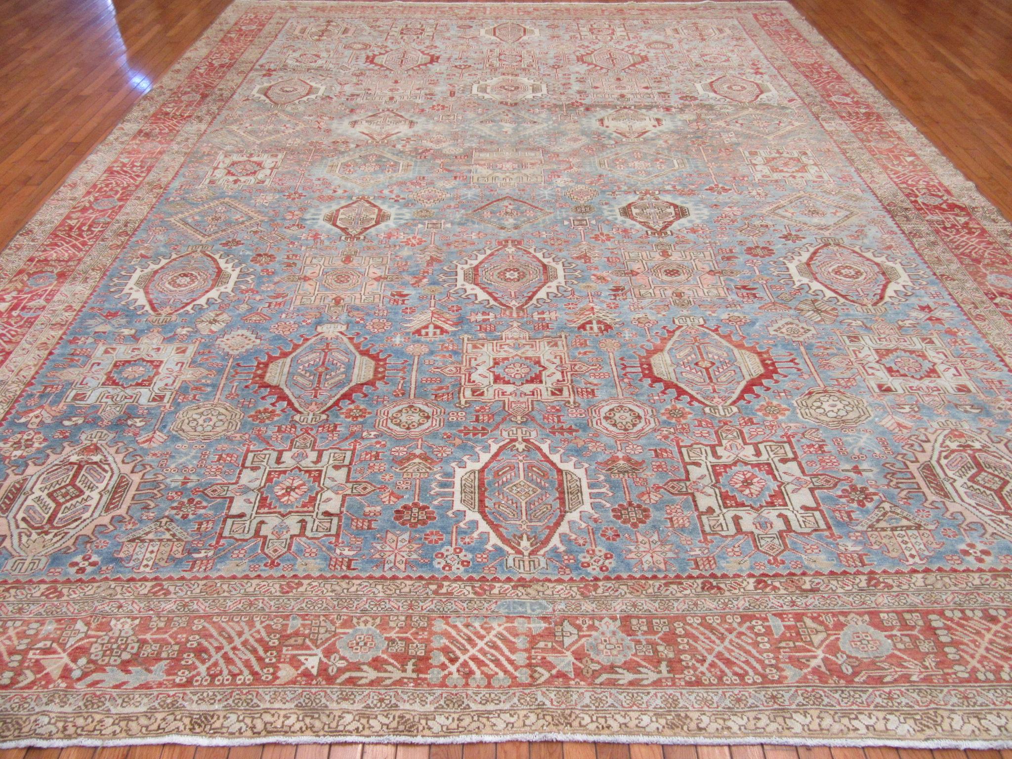 This is an antique hand knotted Persian Karajeh rug . It has been antique washed to reduce the colors and light distressed look. The rug has the traditional all-over pattern with repetitive geometric medallions that is the trade mark of the Karajeh