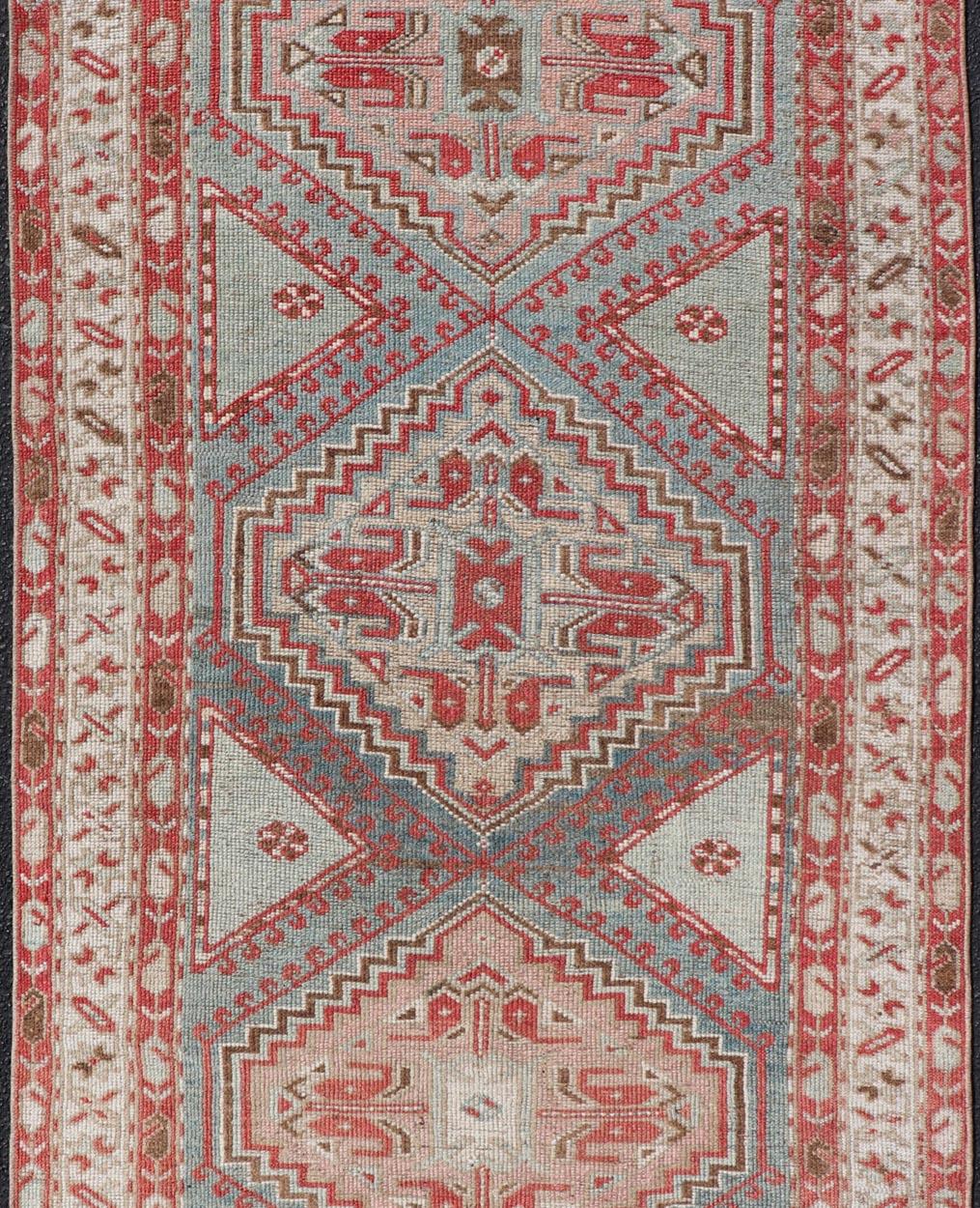 This antique Persian Kurdish rug has been hand-knotted in wool and features a sub-geometric medallion design rendered in multicolor. A complementary, multi-tiered border encompasses the entirety of the piece; making it a marvelous fit for a wide