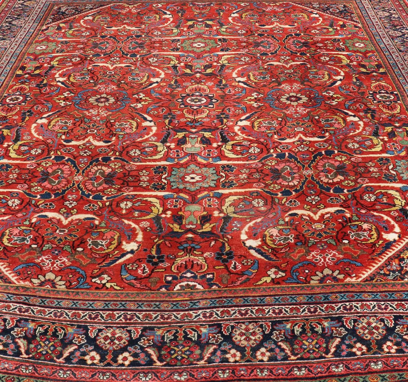 Dieses antike persische Mahal-Sultanabad zeichnet sich durch ein großes zentrales Rautenmuster aus, das mit floralen und subgeometrischen Motiven in mehreren Farben auf rotem Hintergrund verziert ist. Das gesamte Stück ist von einem komplementären,