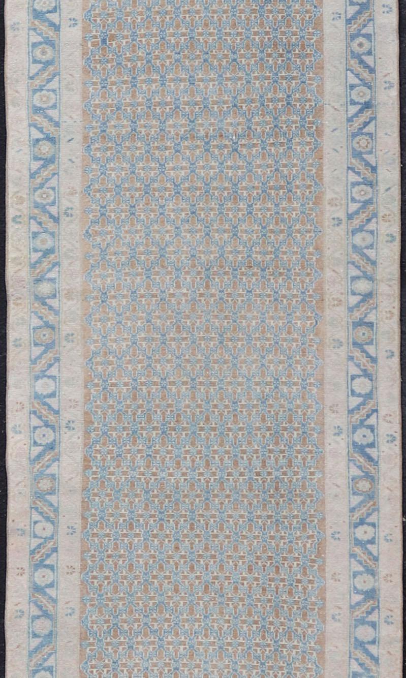 This Antique Persian Malayer runner features an all-over symmetrical sub-geometric design, enclosed within a complementary multi-tiered border. The entirety of the runner is rendered in blue, brown and ivory hues; making this rug a perfect fit for a