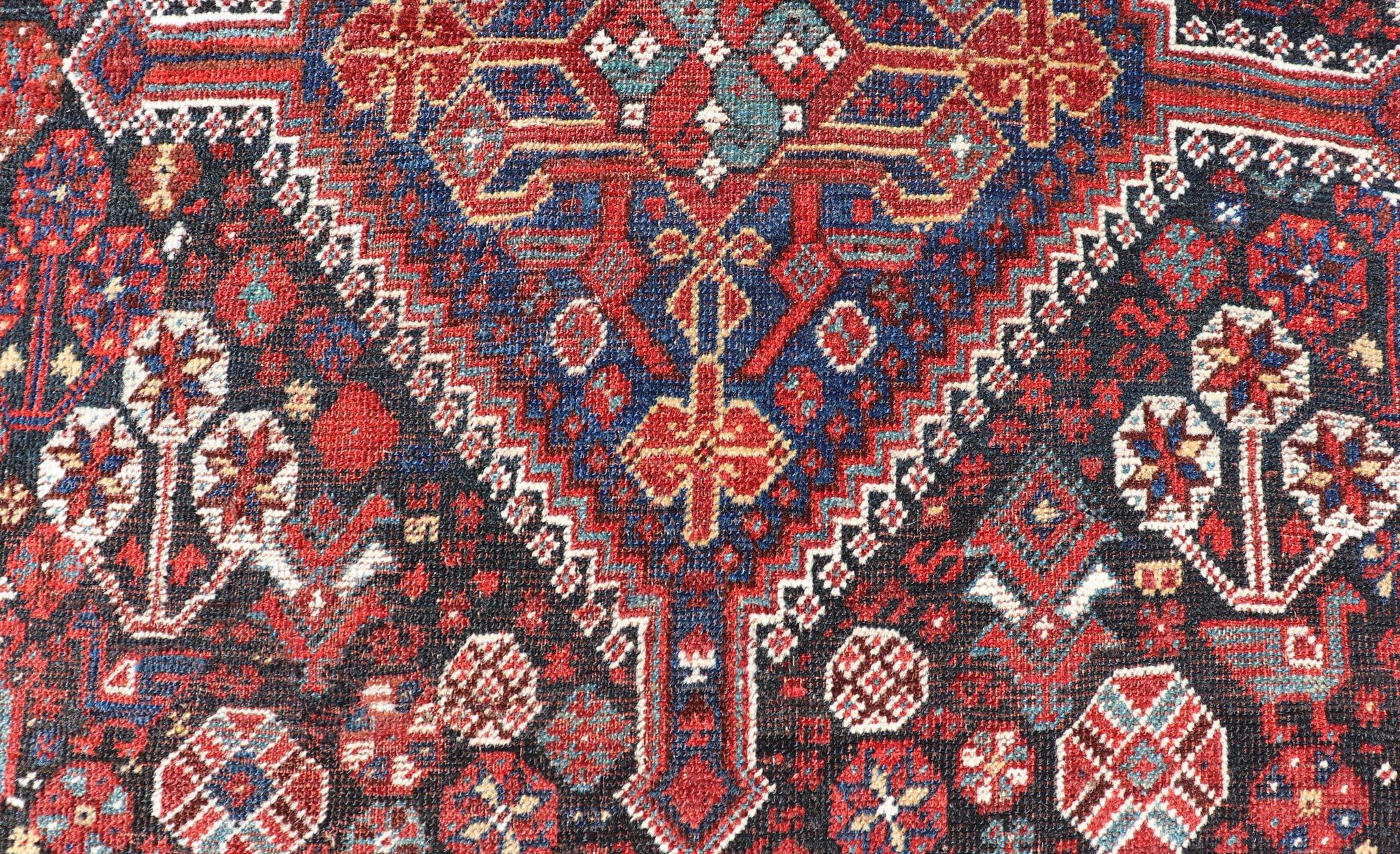 Cet antique tapis persan Qashqai a été noué à la main en laine et présente un motif subgéométrique multicolore. Une bordure complémentaire à plusieurs niveaux englobe la totalité de la pièce, ce qui lui permet de s'adapter merveilleusement à une