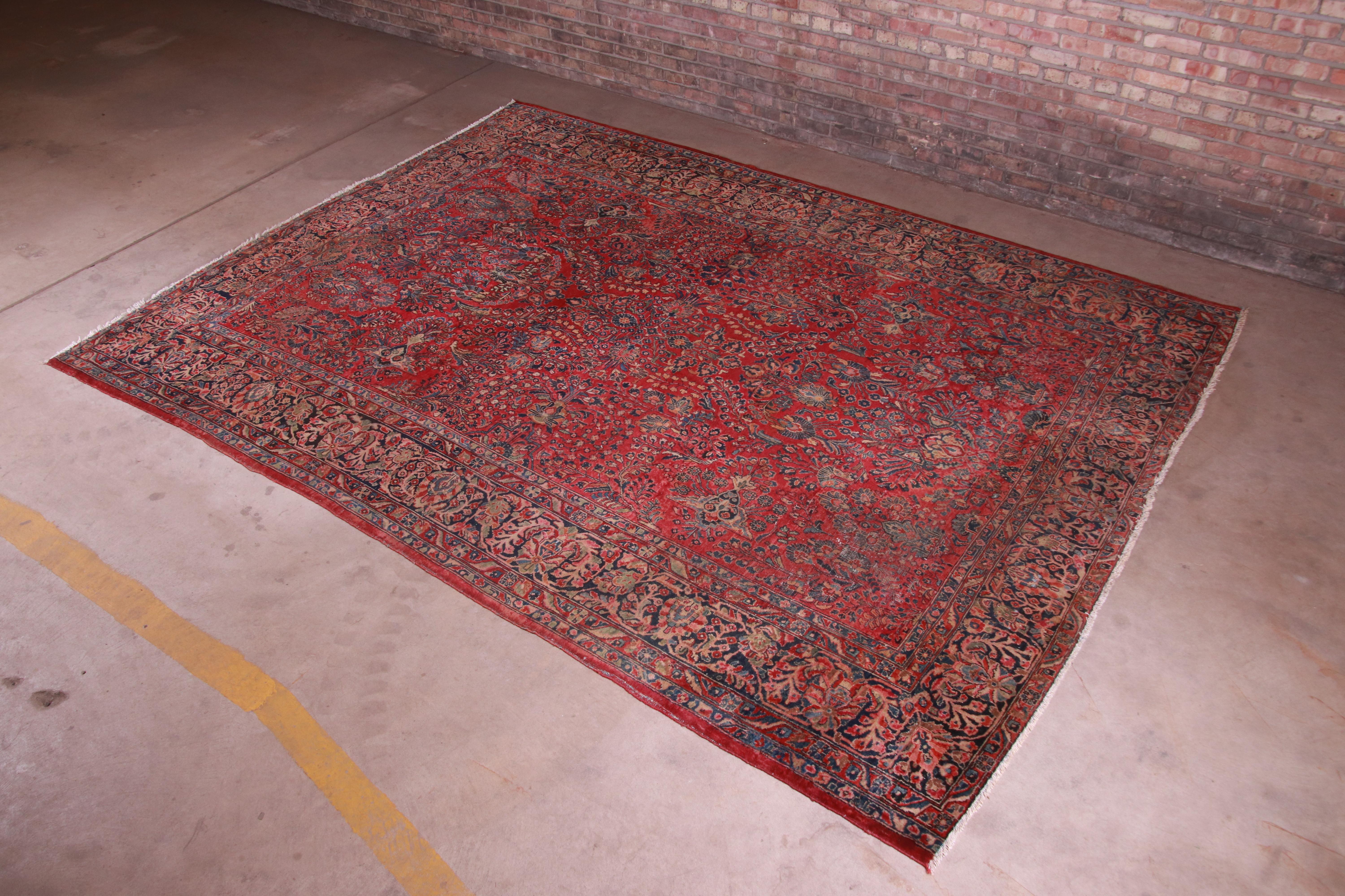 A gorgeous antique hand knotted Persian Sarouk room size rug.

Persia, circa 1930s

Classic design with floral sprays and bouquets

Measures: 8