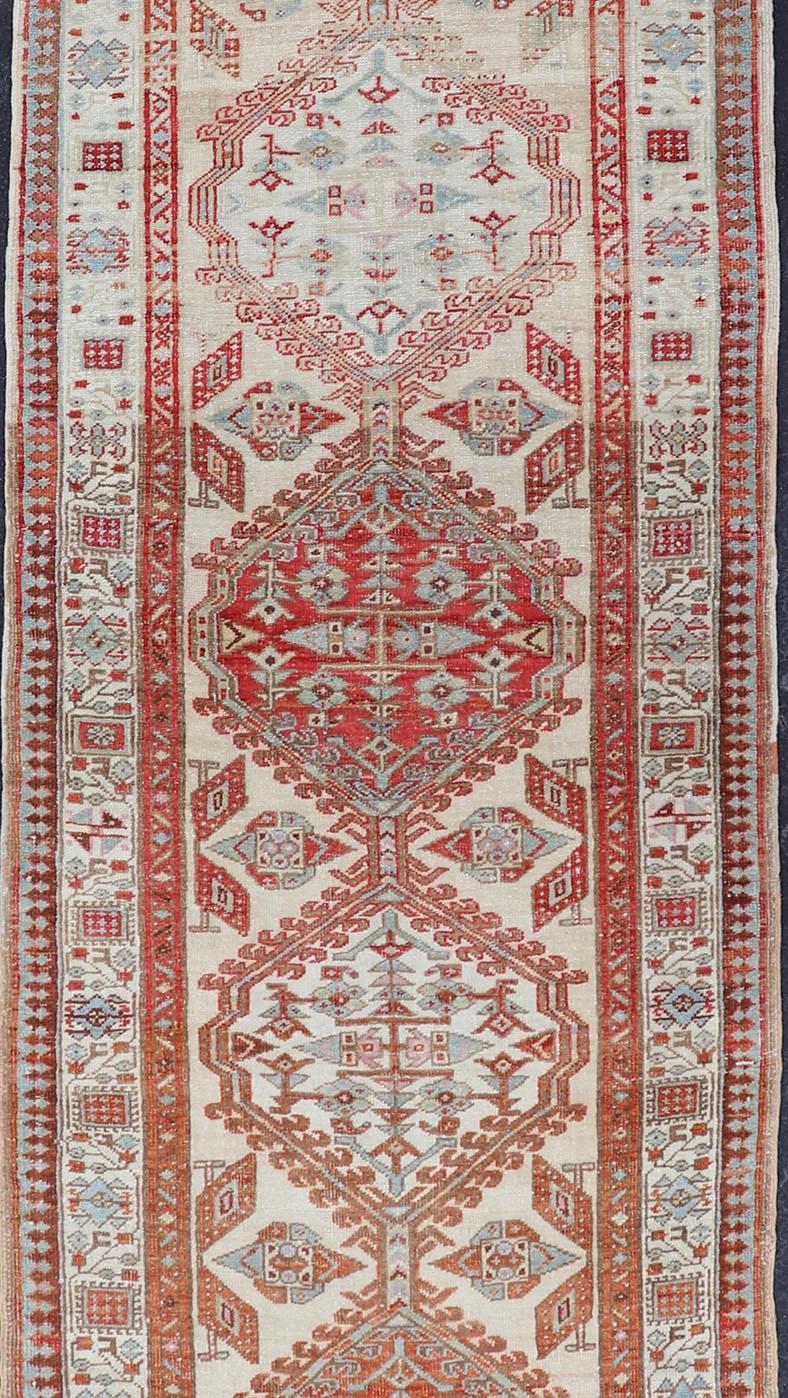 This antique hand-knotted Sarab runner features a Sub-geometric design accentuated by various motifs. The entirety of the piece is enclosed within a complementary, multi-tiered border; making this rug an excellent fit for a variety of interiors.