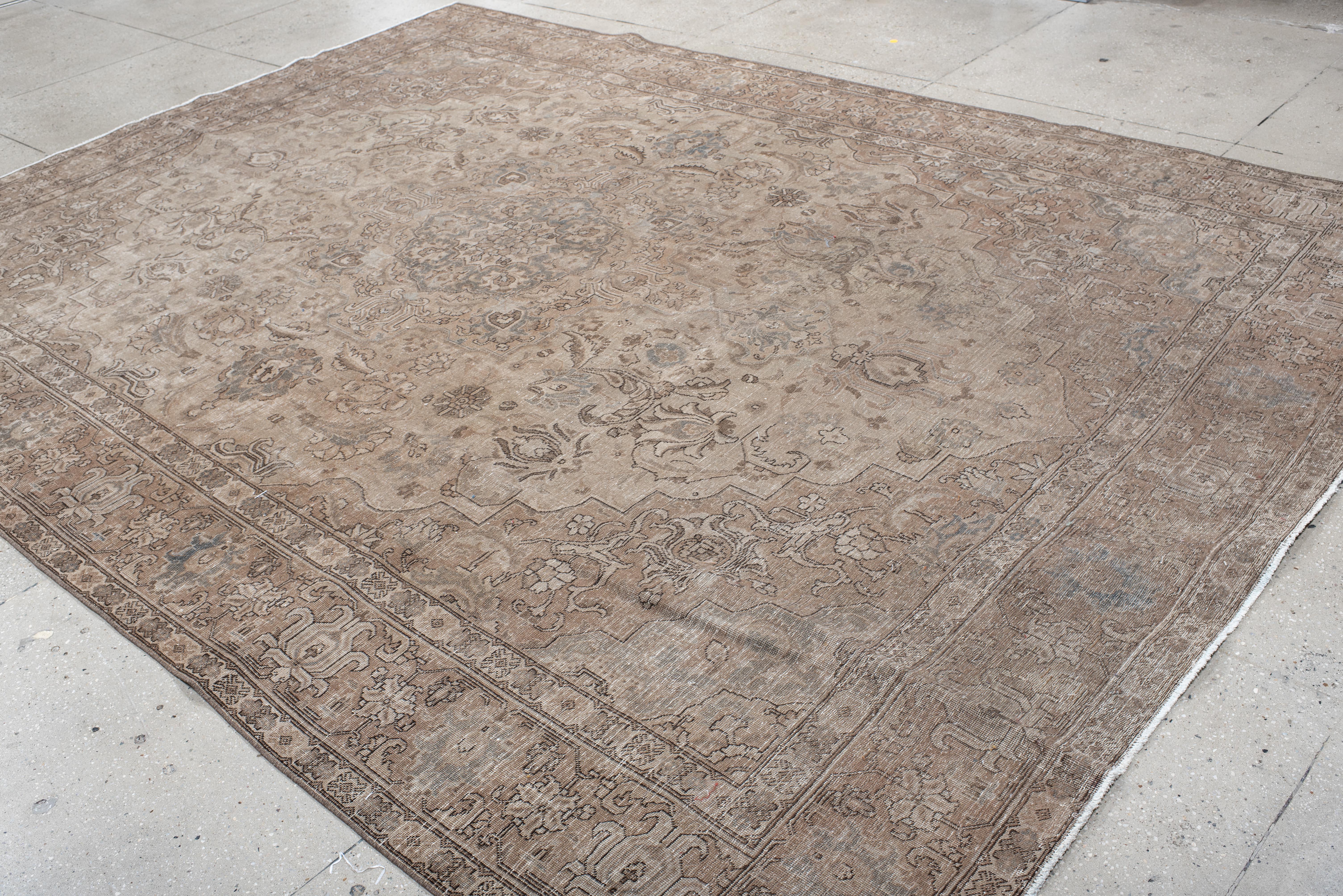 Dieser antike Teppich aus Täbriz zeigt ein wunderschön gewebtes zentrales Medaillon, das von komplizierten Blumenmotiven und detaillierten Arabesken umgeben ist und die raffinierte Kunstfertigkeit der persischen Handwerkskunst veranschaulicht. Die