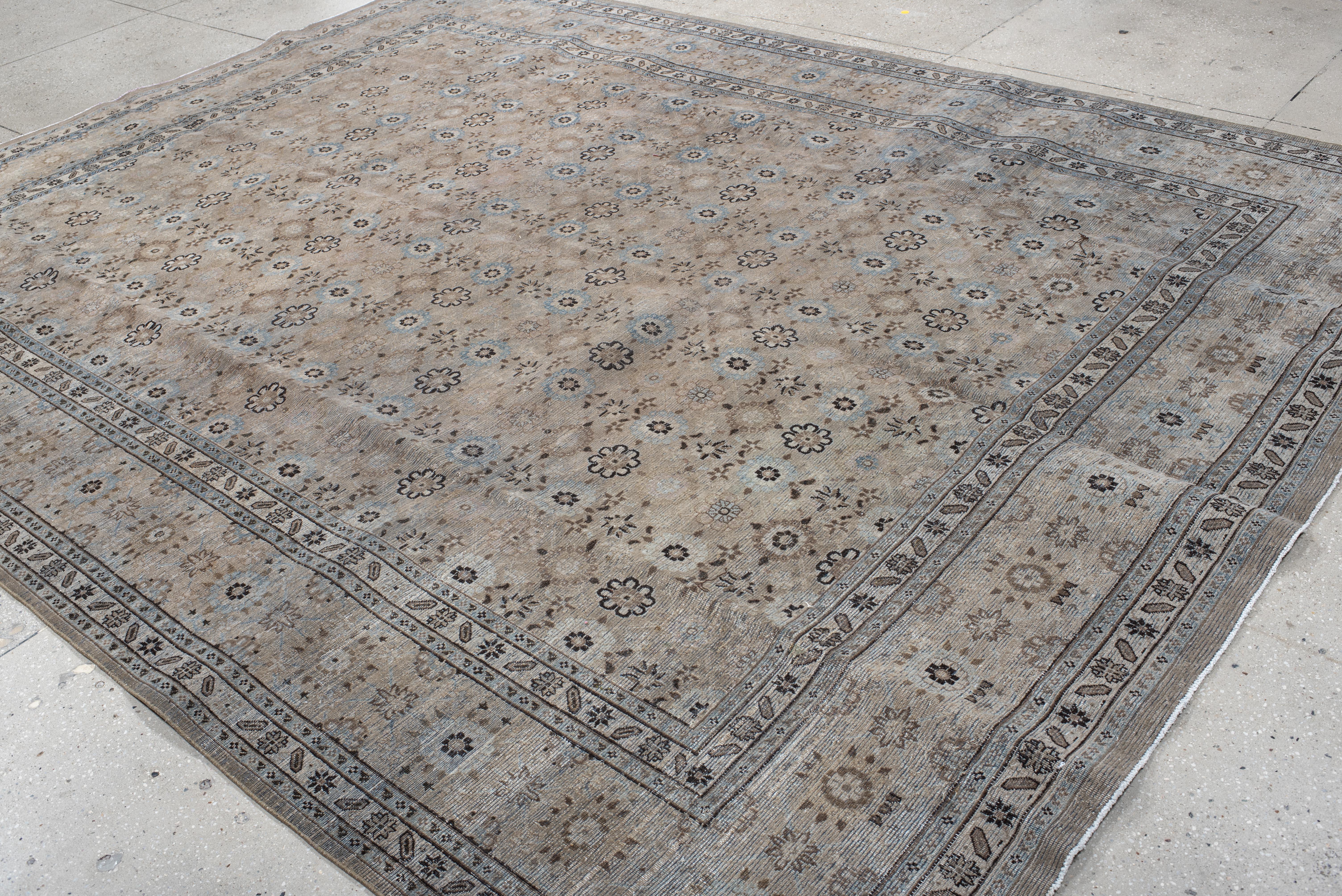 Esta alfombra antigua Varamin presenta un diseño de rejilla floral meticulosamente anudado a mano, dispuesto en un patrón simétrico que crea una estética armoniosa y estructurada. Los tonos suaves de beige, topo y azul pálido realzan su presencia