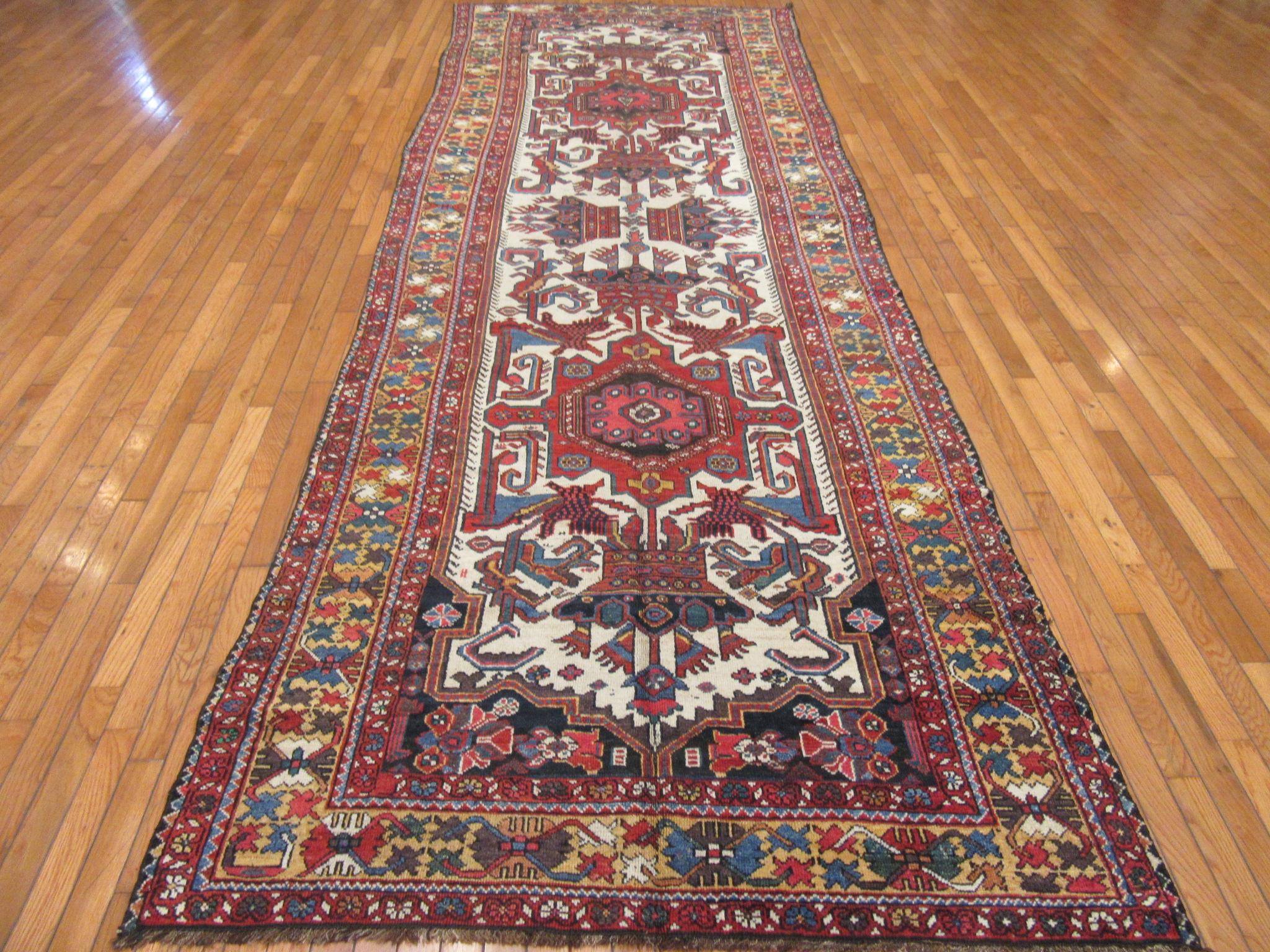 This is an antique hand knotted Persian Kurdish Baktiary rug in a traditional nomadic design featuring the crown motif on an ivory color field. The rug is made with all wool and natural dayes. It measures 4' 8'' x 14' 4'' and in very good condition.