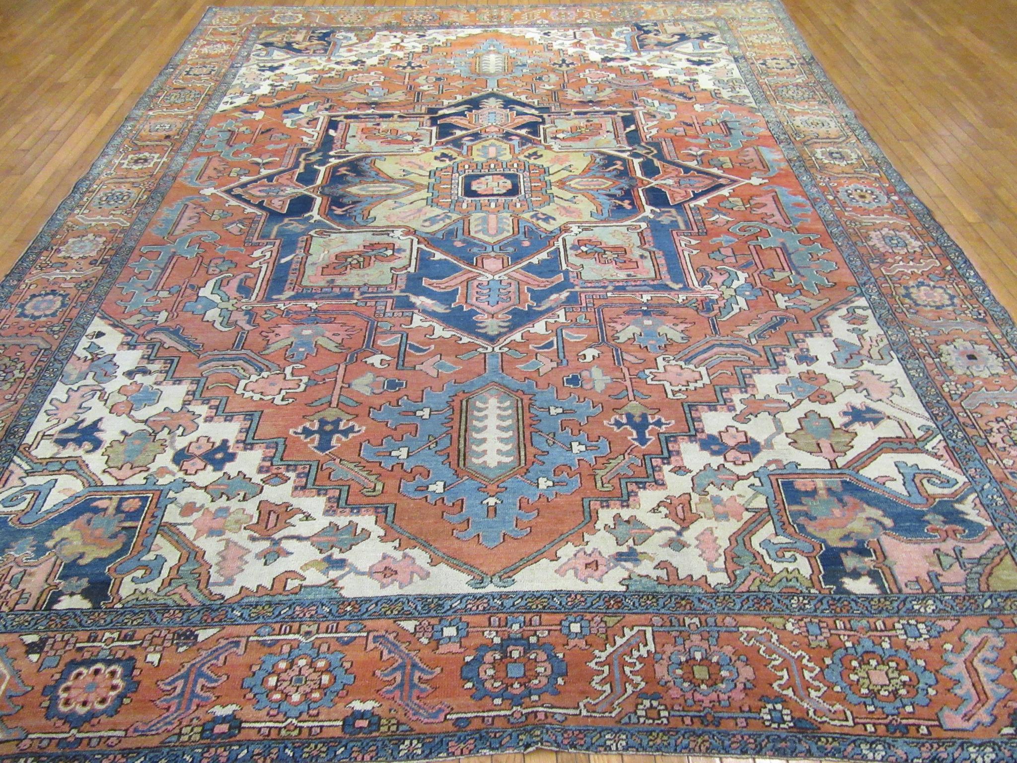 This is an antique hand knotted room size Persian Serapi rug. It is made with wool on cotton foundation in the Classic traditional geometric central and corner medallion design a trade mark of rugs coming from this region. The rug measures 10' x 13'