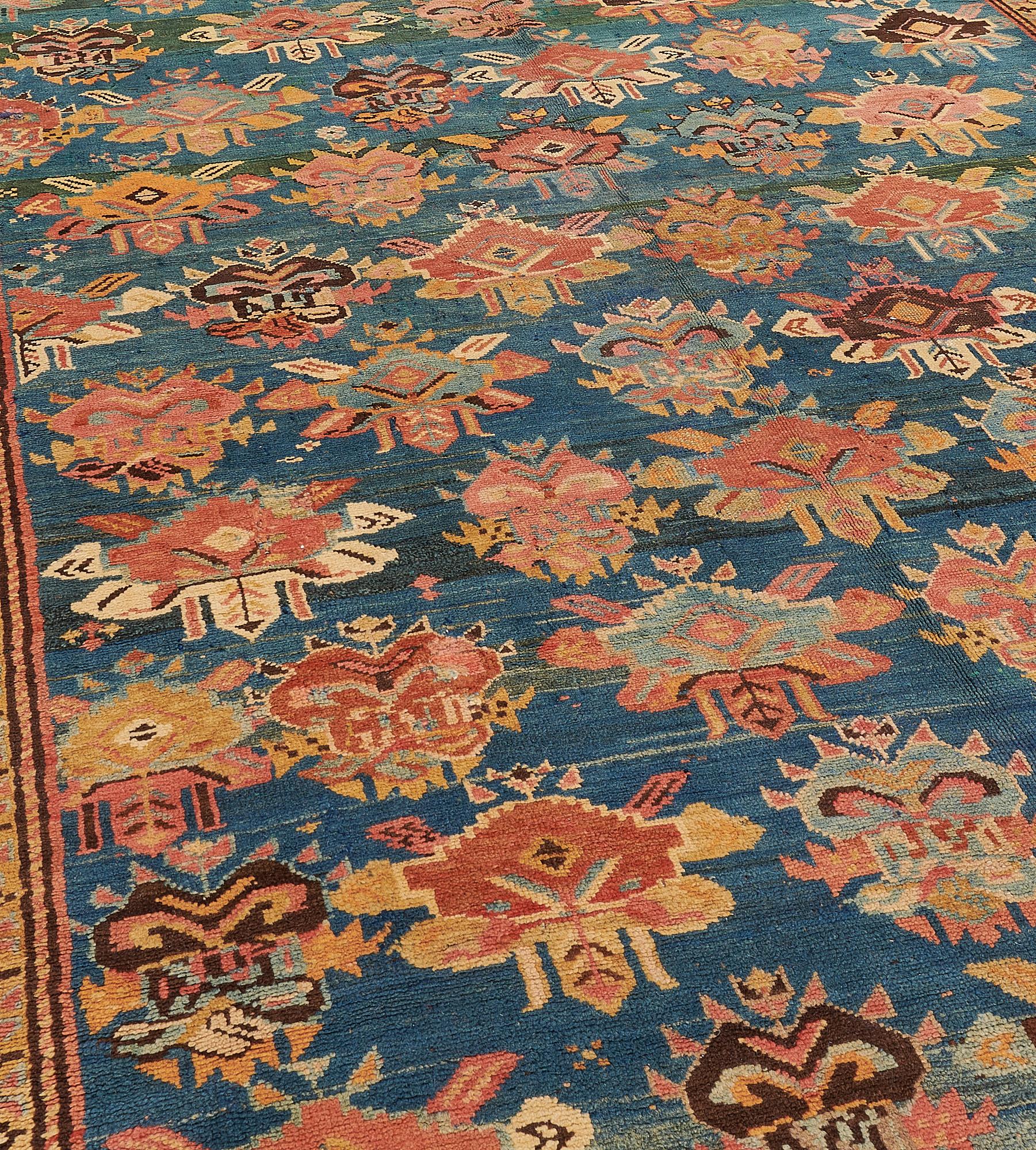 Dieser antike Karabagh-Teppich (um 1900) hat ein smaragdgrünes Feld mit diagonalen Reihen polychromer, eckiger Blumensträuße, die von winzigen Blütenköpfen und eckigen Blumenmotiven umgeben sind, in einer schmalen, sandgelben, eckigen