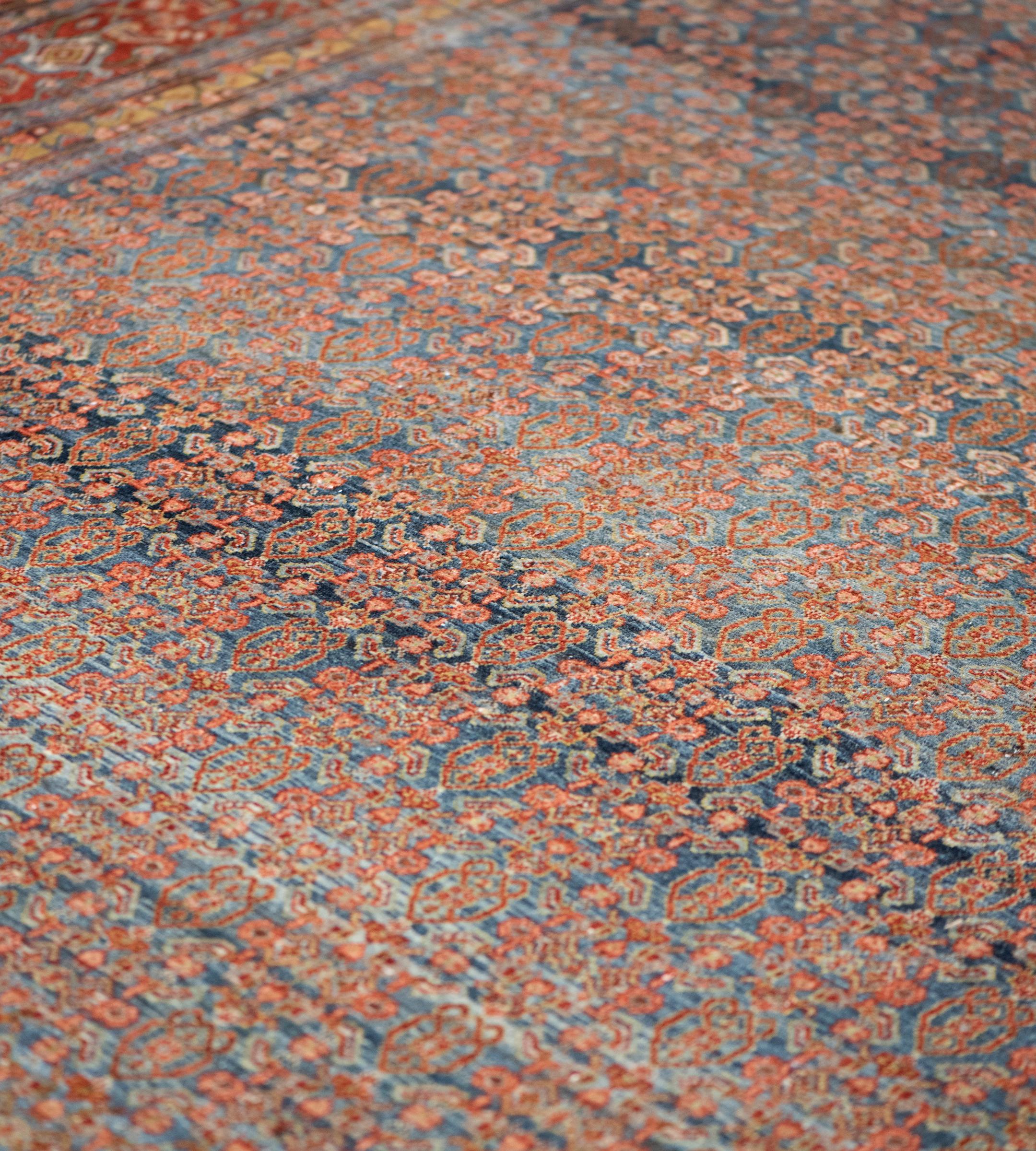 Cet ancien tapis persan Seneh a un champ bleu marine nuancé avec un délicat motif herati polychrome, dans une bordure rouge brique de palmettes de tortue polychromes reliées par des vignes florales angulaires entre des bandes florales angulaires