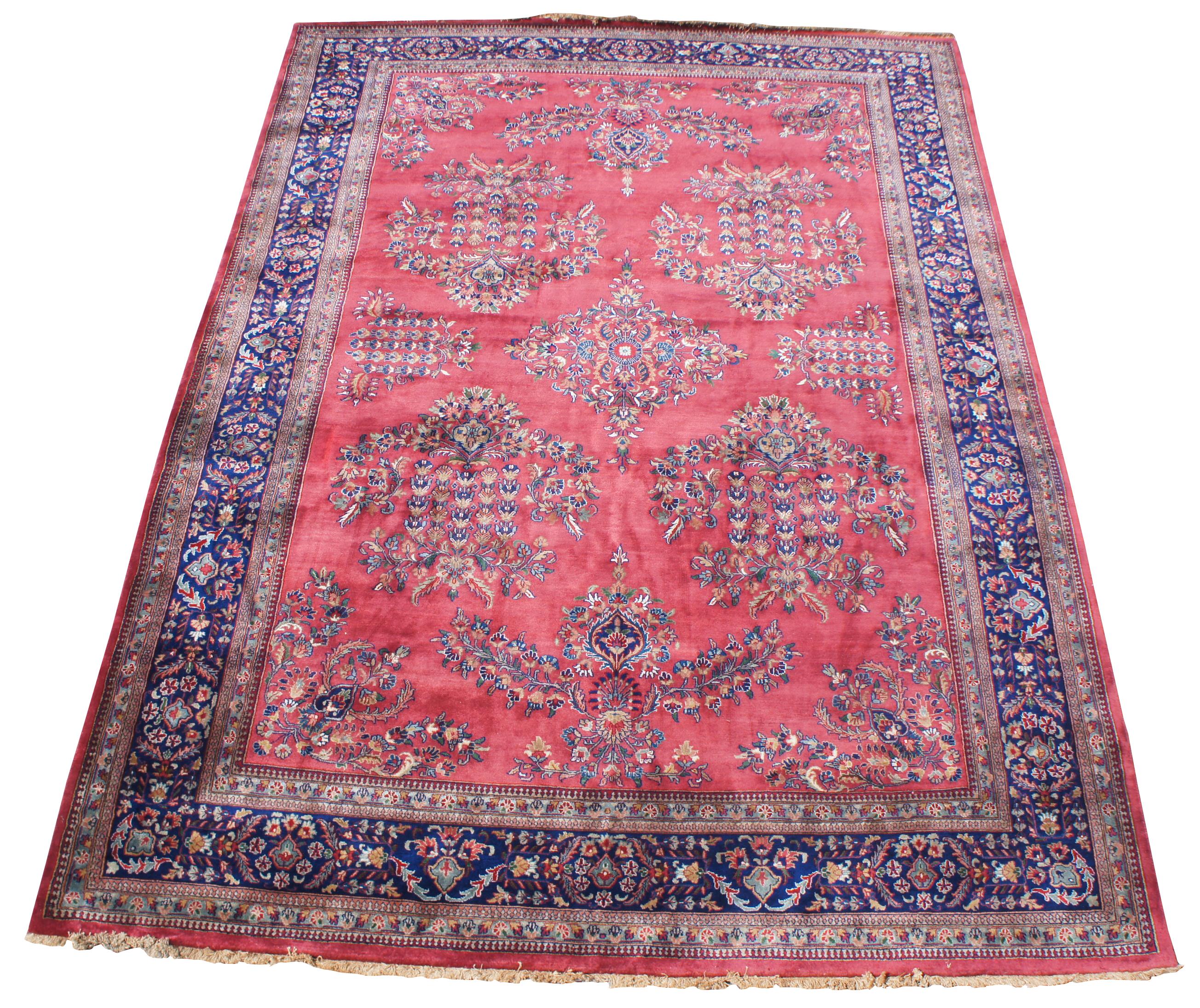 Antique hand knotted Sarugh area rug. Features a field of red with a floral spray of medallions and all over floral design, framed by a indigo / blue / purple border. Features blues, purples, reds, pinks, green and cream / beige. Measures: 9' x