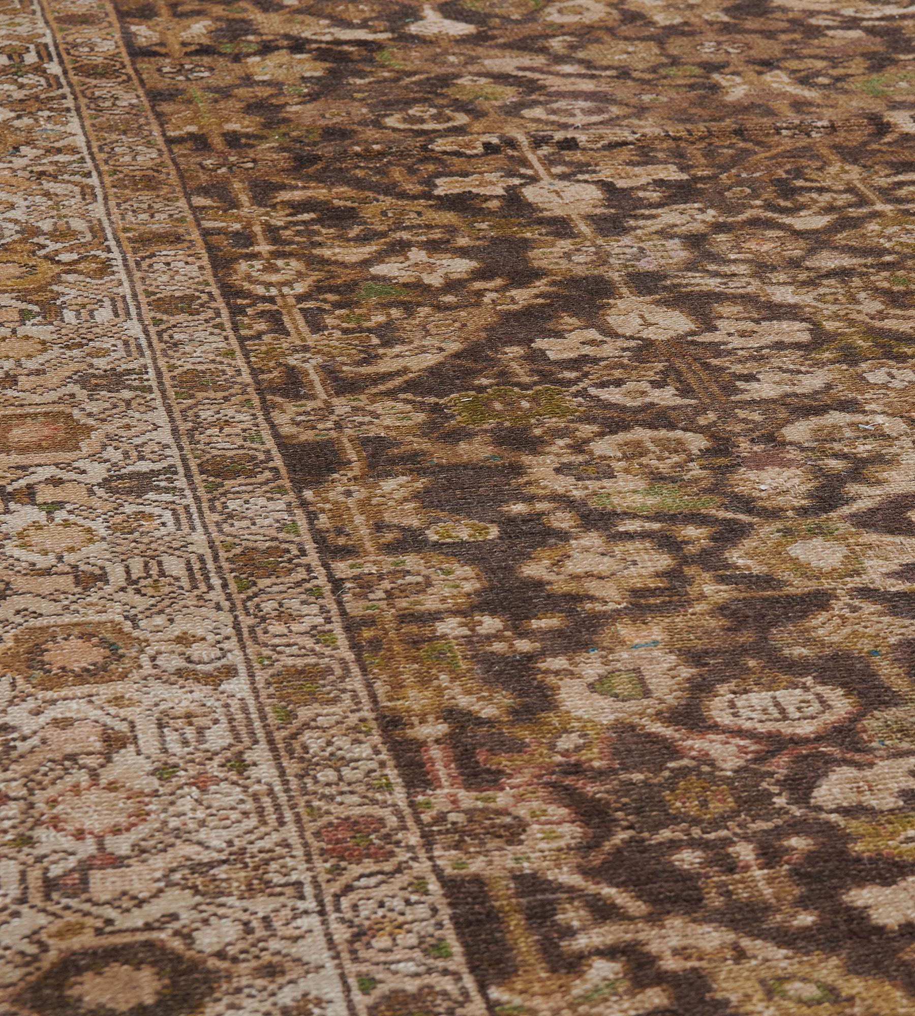 This antique Malayer rug has a chocolate-brown field with an overall design of diagonal rows of linked lozenges each containing dense ivory, sandy-yellow and lime-green angular floral vine, in an ivory border of chocolate, sandy-yellow and