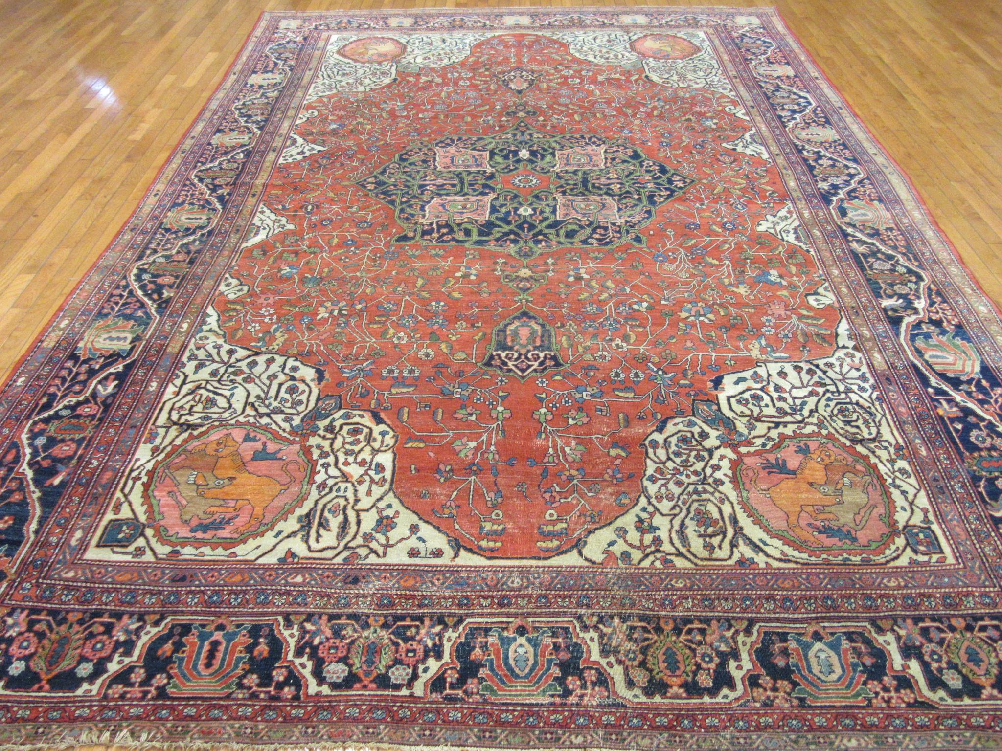 This is an antique hand-knotted Persian Sarouk Farahan rug made with wool colored with all natural dyes on a cotton foundation. The rug has a very unique finely hand knotted traditional corner and central medallion design with animal prints in the
