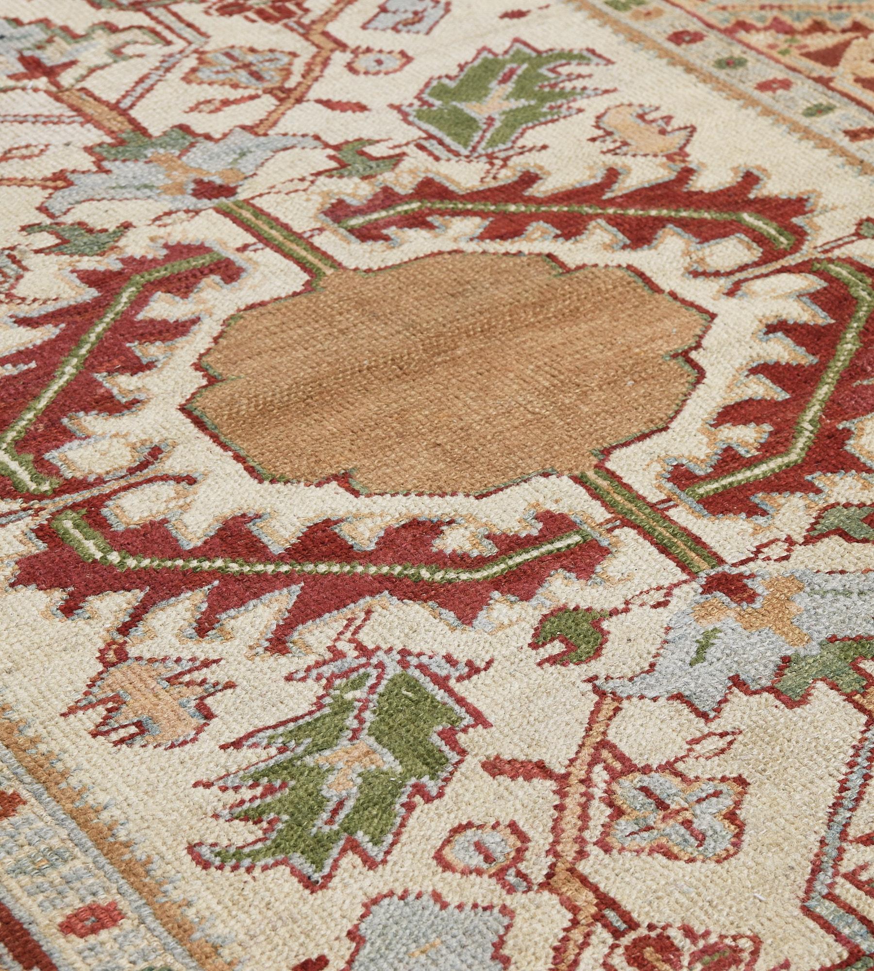 This antique Serapi rug features an ivory field with a large central caramel-brown stepped medallion enclosed within a bold brick-red band of serrated leaves and issuing a bold polychrome palmette and floral and leafy vine, in a broad brick-red