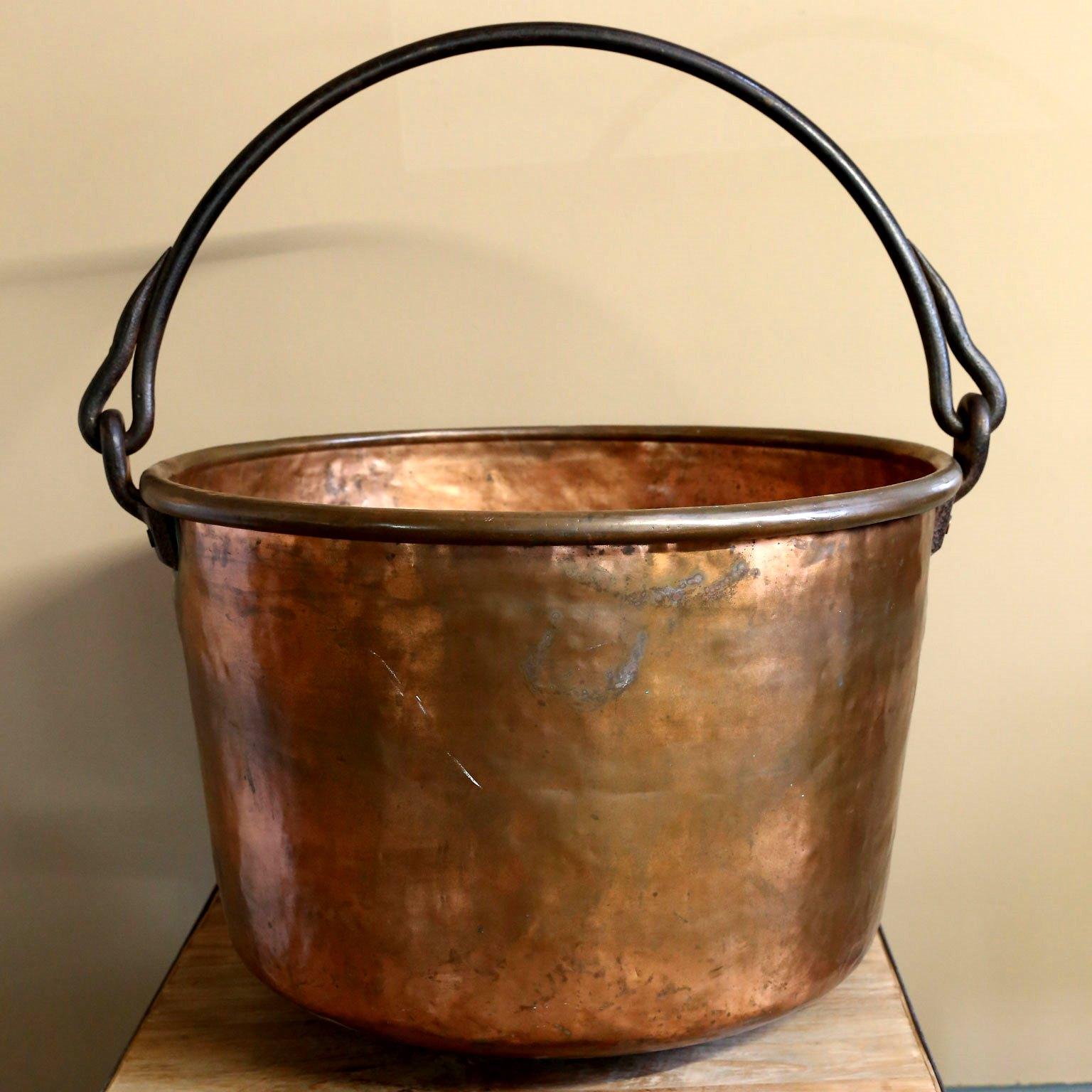 This antique copper apple butter kettle was made in the US. It was handmade and hand-hammered and the iron handle was forged. It is a beautiful object and would be great as to hold logs, etc. The pure and simple lines are pleasing and timeless. Its