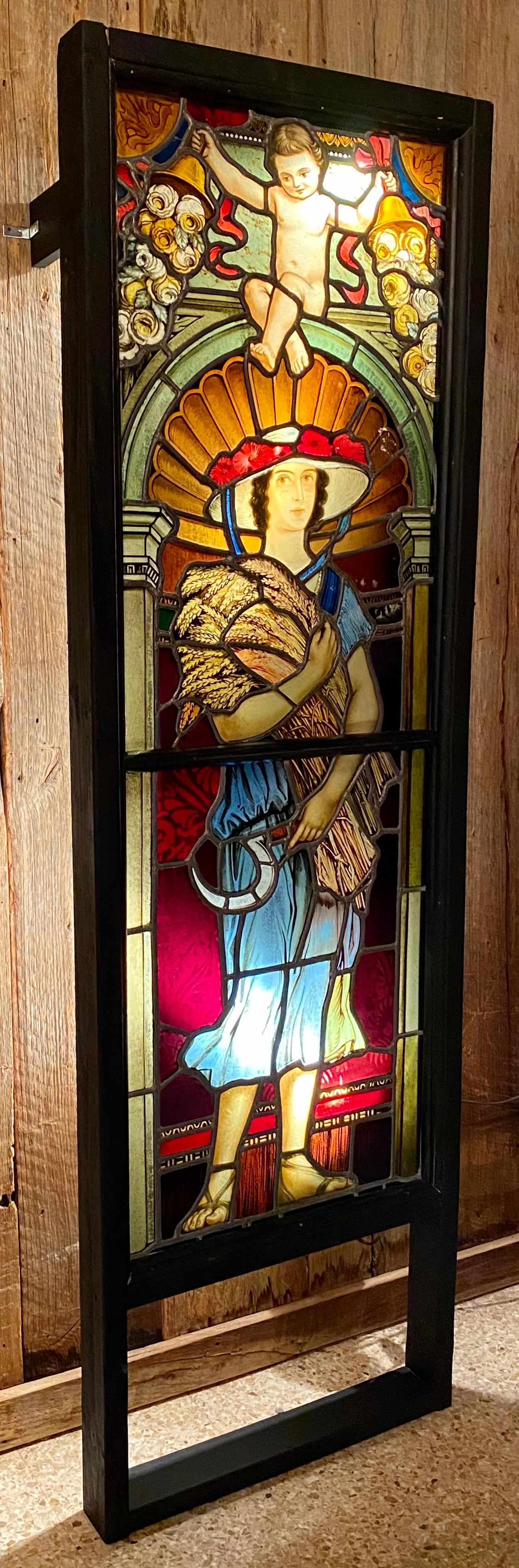 Antique hand painted 19th century stained glass panel window depicting a woman holding a bushel of wheat, circa 1900.
A perfect example of painted stained glass—small glass pieces vibrantly colored with metallic minerals (cobalt for blue, gold for
