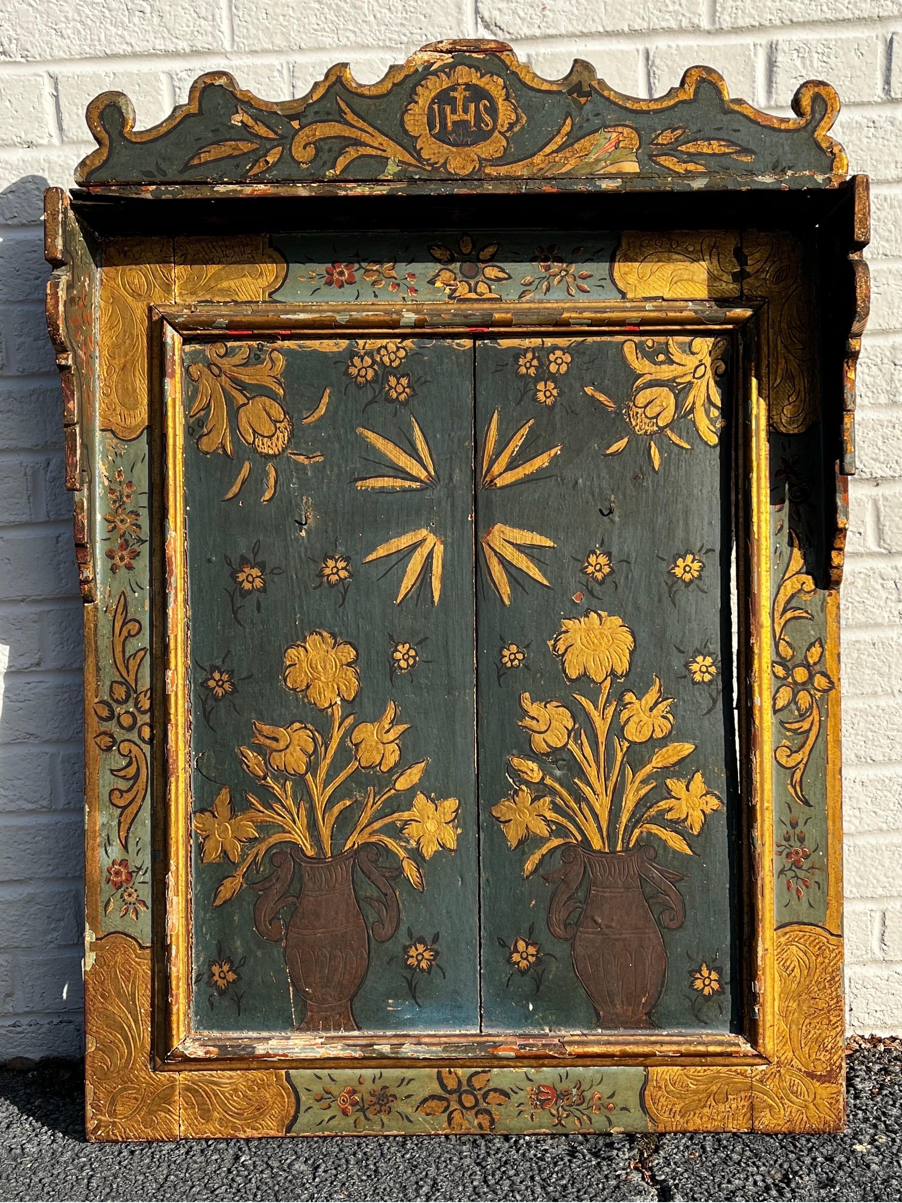 An antique circa 1880's late 19th century hand painted, carved, incised and partially gilt religious creche or wall hanging cabinet reliquary. This item would have displayed a cross or other religious symbol. The JHS insignia at the top of the piece