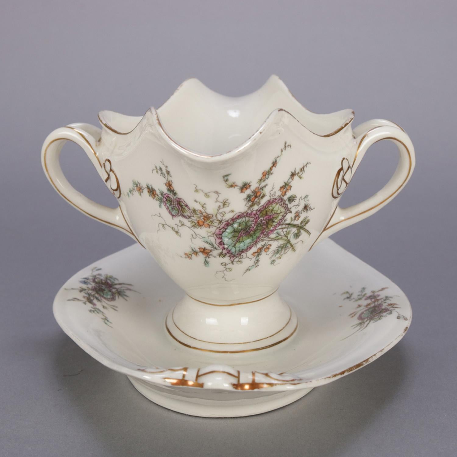Antique Limoges School porcelain gravy boat features oval form with attached under plate and having hand-painted enamel over transfer garden setting design to include floral and foliate motif, gilt trimming, circa 1990.

***DELIVERY NOTICE – Due to