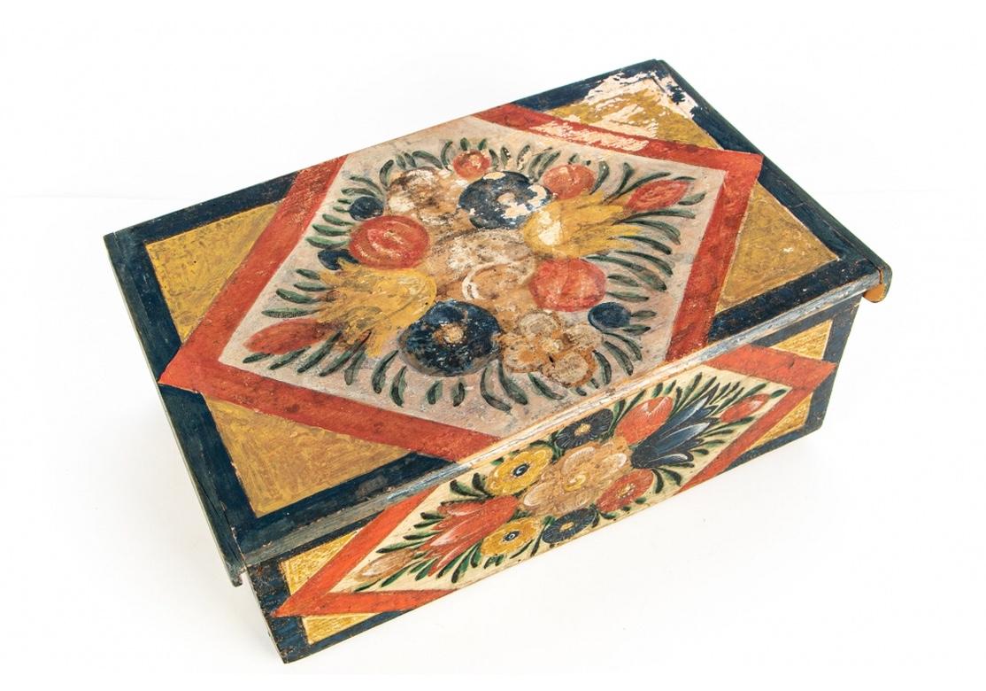 Charming antique Folk Art hand-painted box with multi- colored floral clusters on the lid, front and sides. Deep teal blue borders and shaped sides of the hinged lid. Pale painted and dotted back.
Measures: Length 13