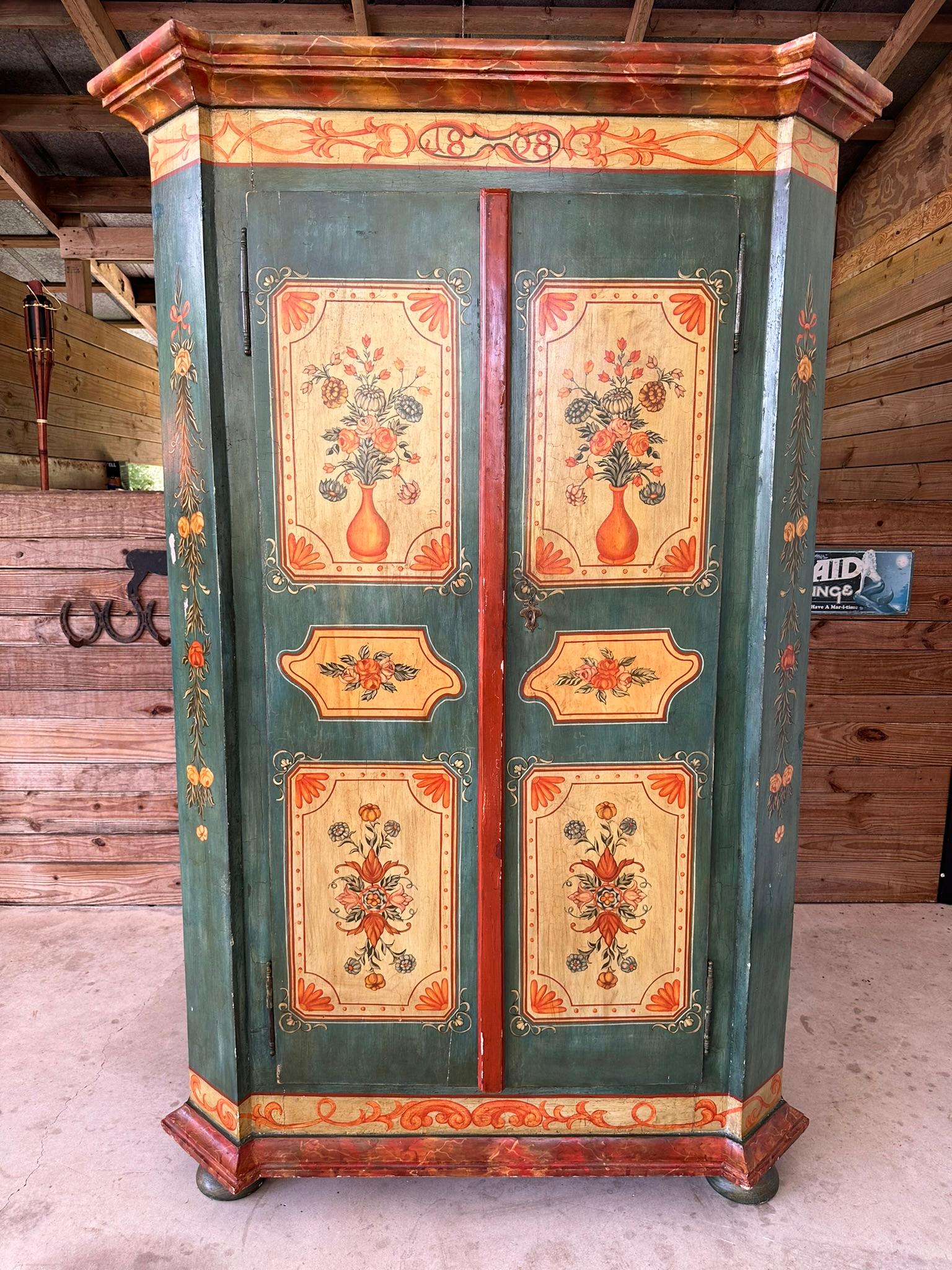 This enchanting antique German “wedding” armoire or cupboard is a stunning example of traditional craftsmanship and artistry.
Hand-painted with intricate floral motifs and vibrant colors, the armoire features charming details that celebrate the