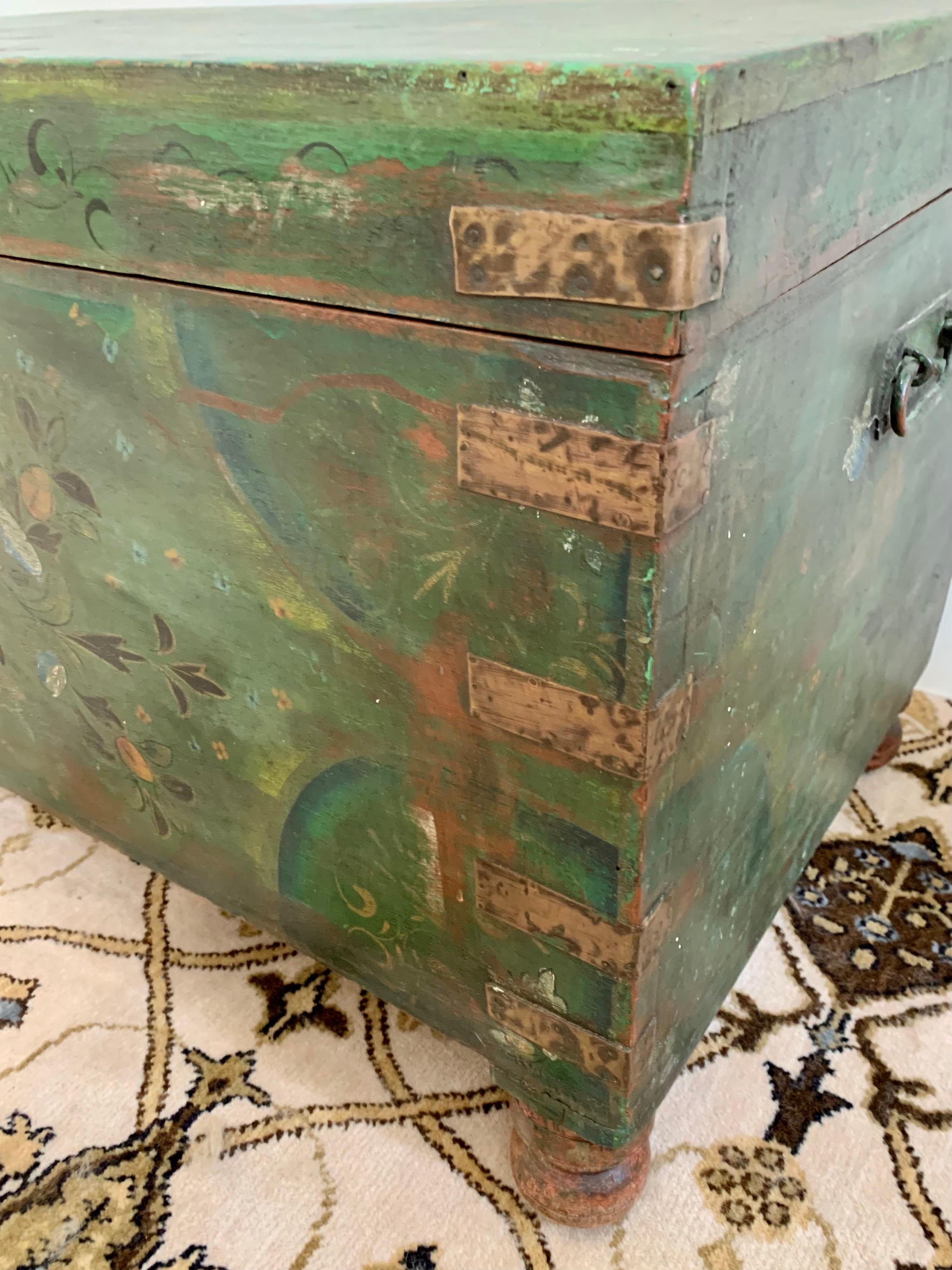 Antique green painted trunk is decorated with a floral motif. Original brass hardware. Features a beautiful distressed finish only acquired through age and use.