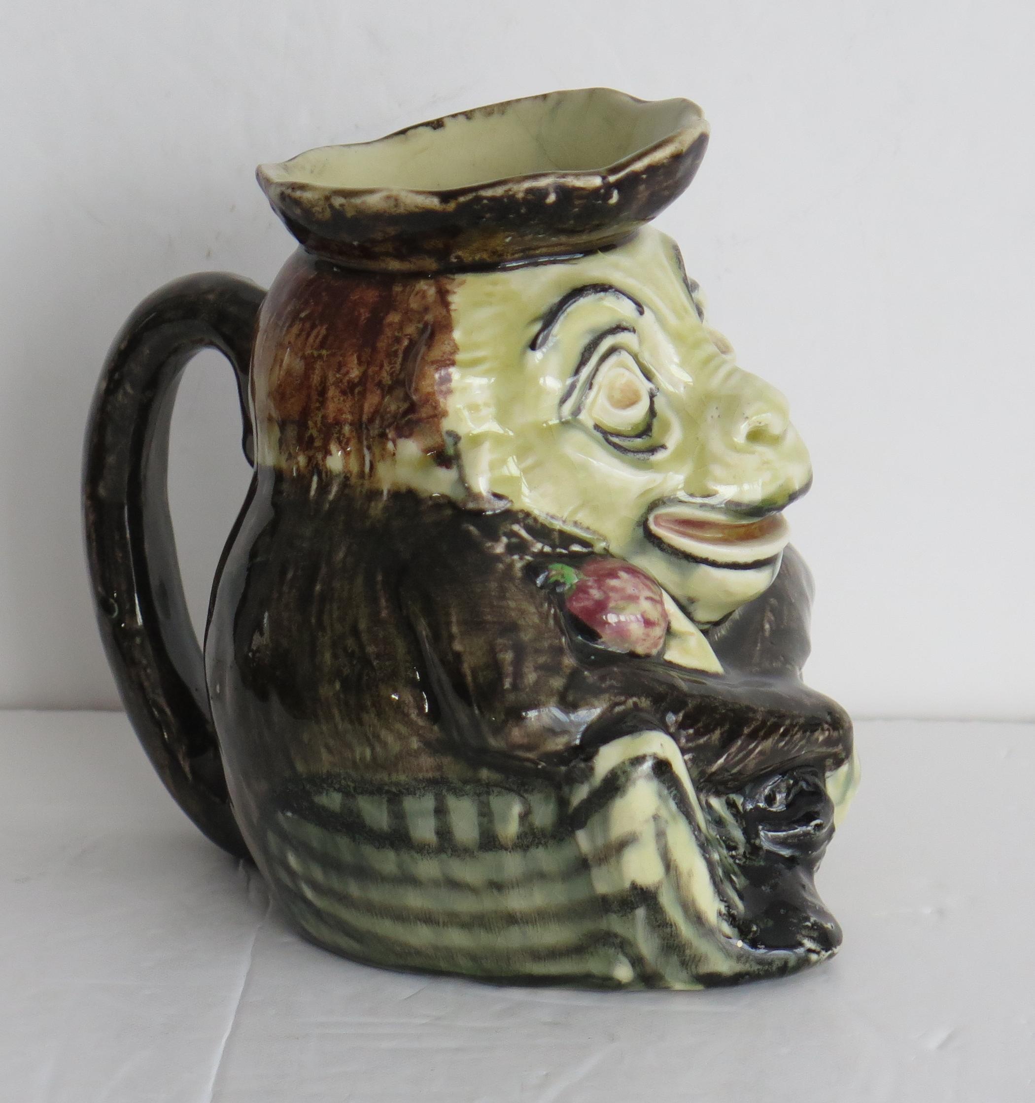 This is a very interesting Pottery Jug of a grotesque Imp or figure holding an apple. 

The jug is well potted in the shape of a grotesque Imp with a loop handle.

The jug is all hand painted with bold coloured enamels.

It has no markings