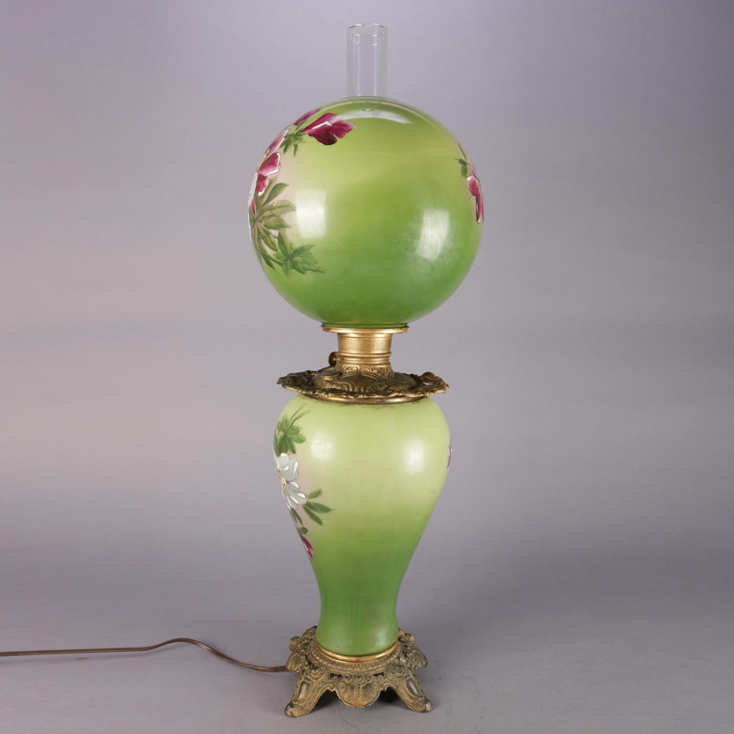 Antique electrified gone-with-the-wind parlor lamp features hand-painted lily on graduated green ground and is seated on pierced scroll and foliated footed base, 