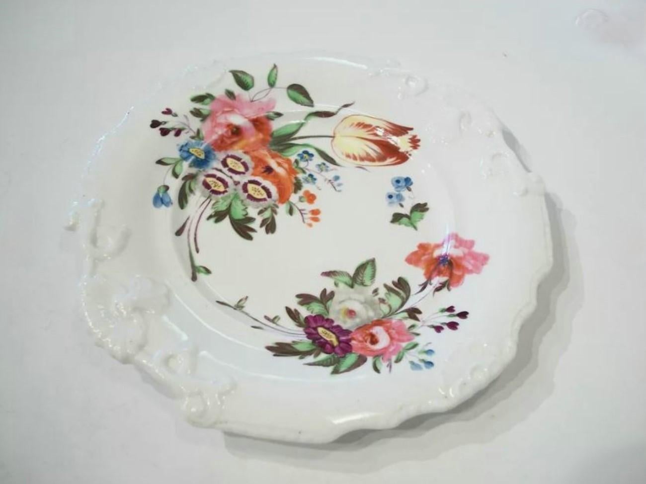 Assiette de cabinet ancienne en porcelaine avec un motif floral peint à la main - bordé de coquillages et de rinceaux en relief - numéro de modèle '3035' peint en puce - non signée - Royaume-Uni (probablement) - fin du 19ème siècle.

Excellent état