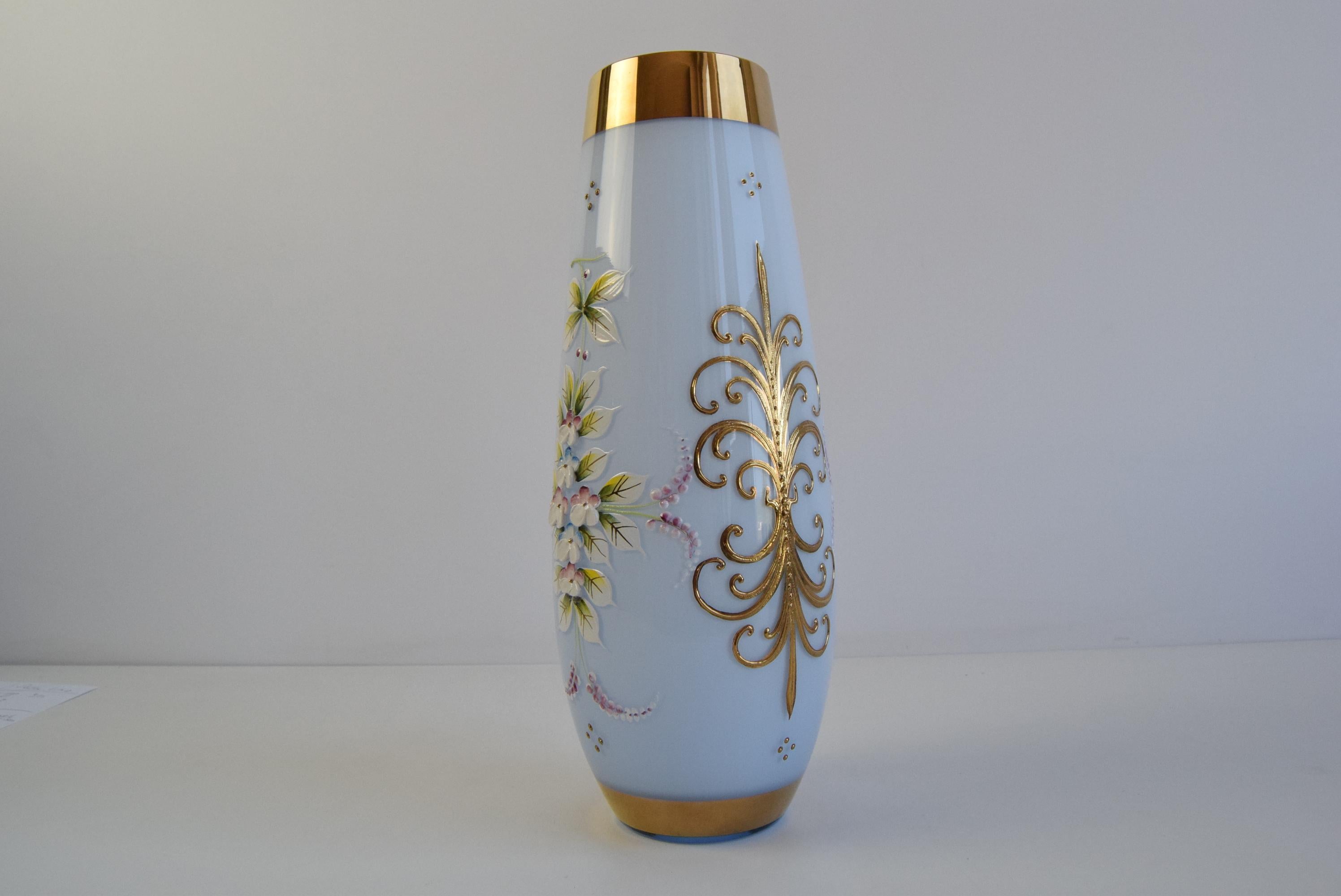 An exquisite antique porcelain vase, beautifully hand-painted with delicate floral motifs and adorned with intricate gold gilded scrollwork. The soft pastel blue glaze serves as a serene backdrop to the vibrant blossoms and elaborate golden