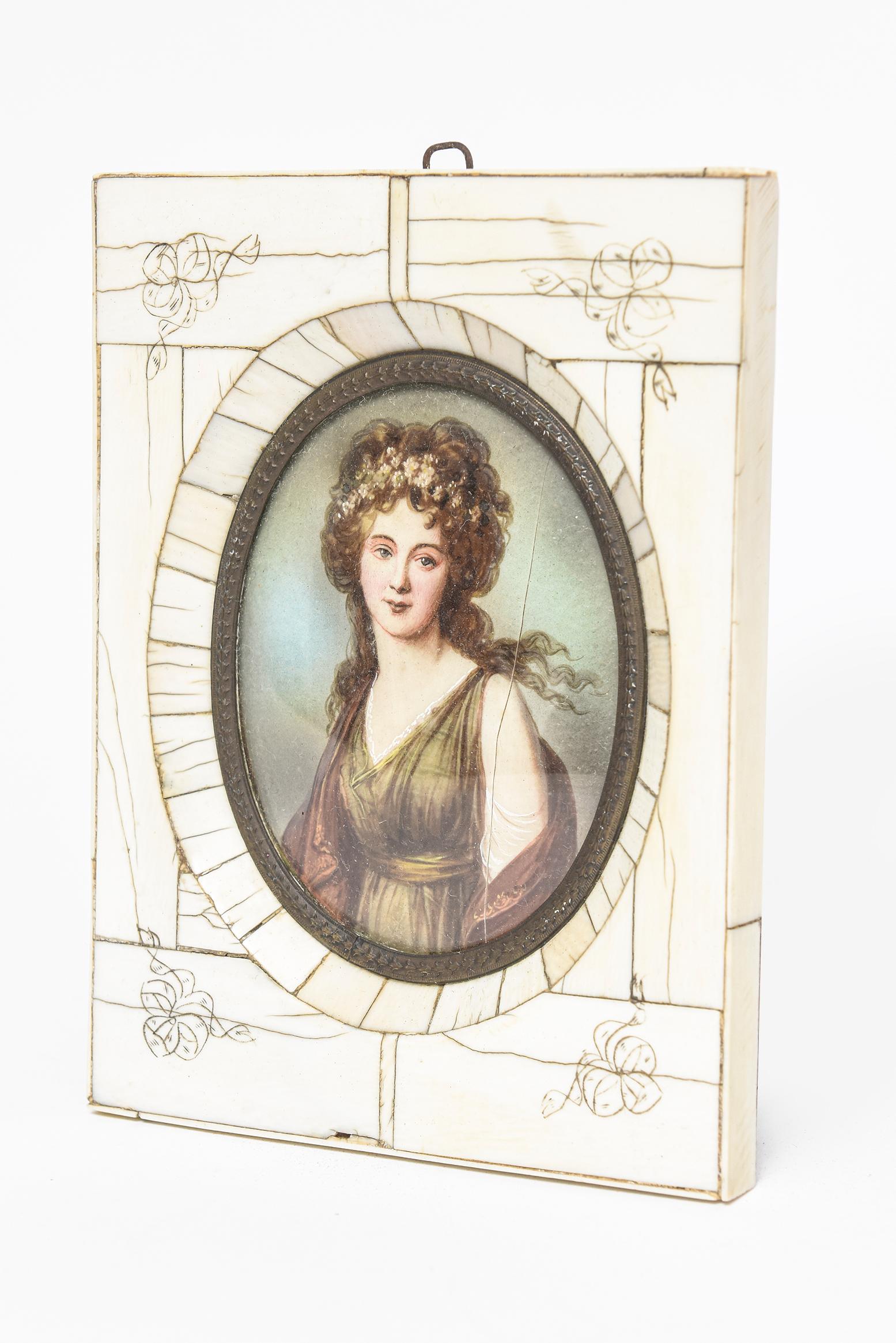 19th century miniature hand-painted portrait of a lady with flowers in her hair presented in an engraved bone rectangular frame with an antique-gilded brass frame.
      