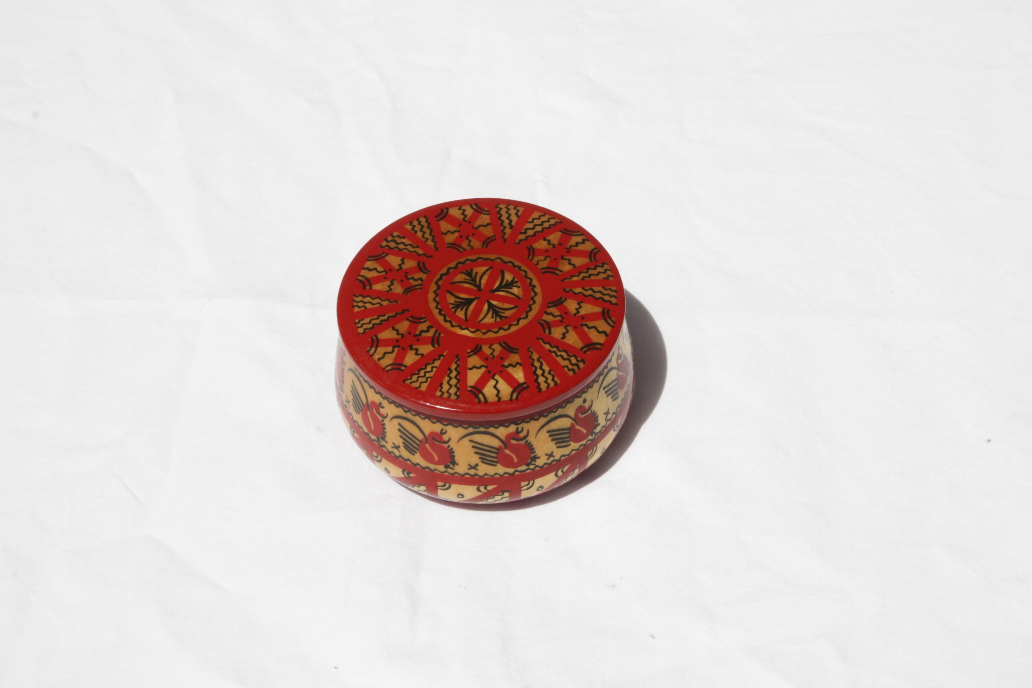 Un petit coffret rond rouge, jaune et noir. Cette boîte vintage peinte à la main sera du plus bel effet sur une commode, une table de nuit ou une table basse. Suffisamment grand pour contenir des épingles à chignon ou des bijoux, son couvercle rond