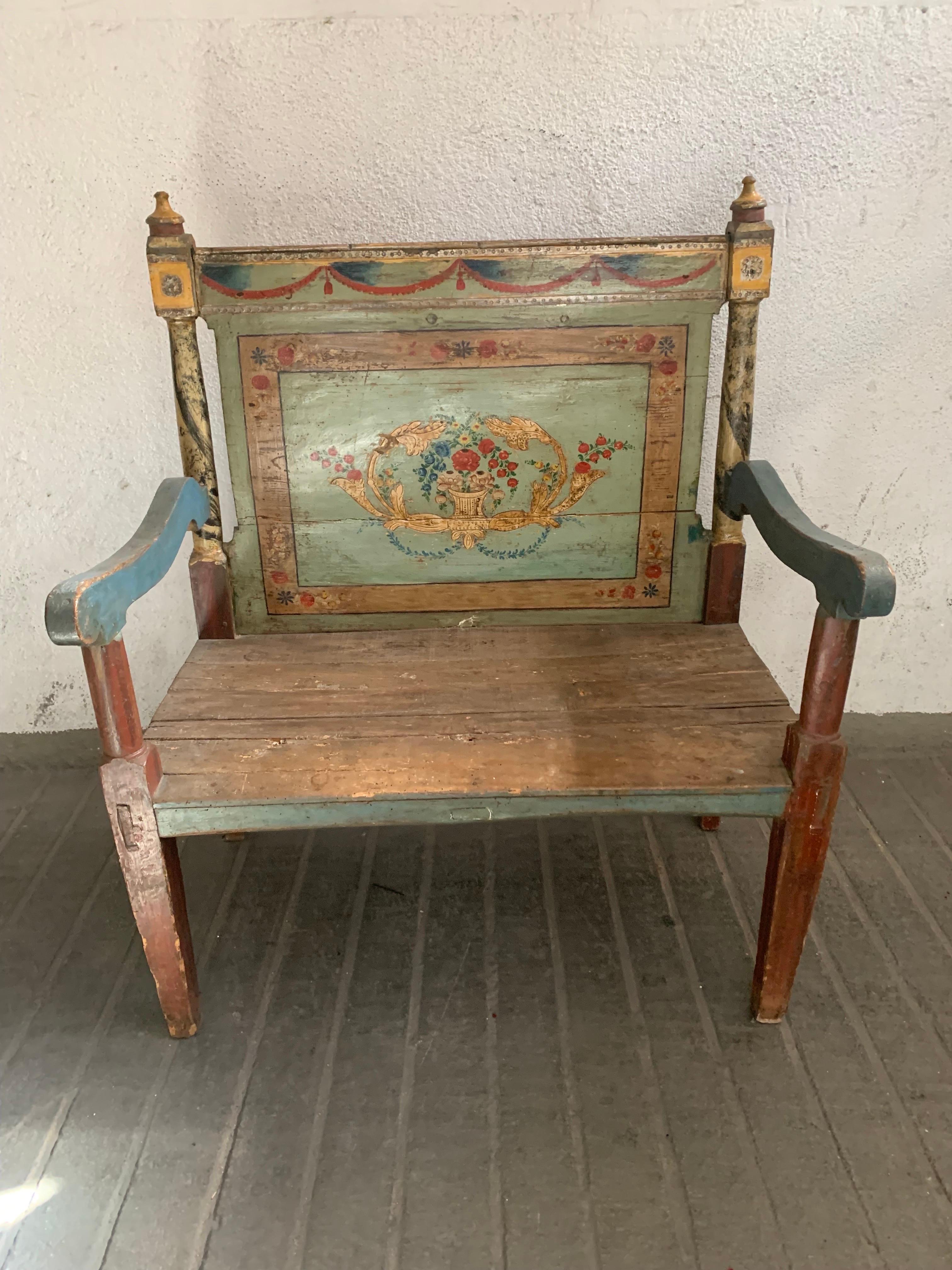 A beautiful bench in rustic style from the beginning of the 19th century, probably from the Aragon area, the backrest has a profusely decorated hand-painted backrest, garlands of flowers and leaves are painted on the top, and in the central part of