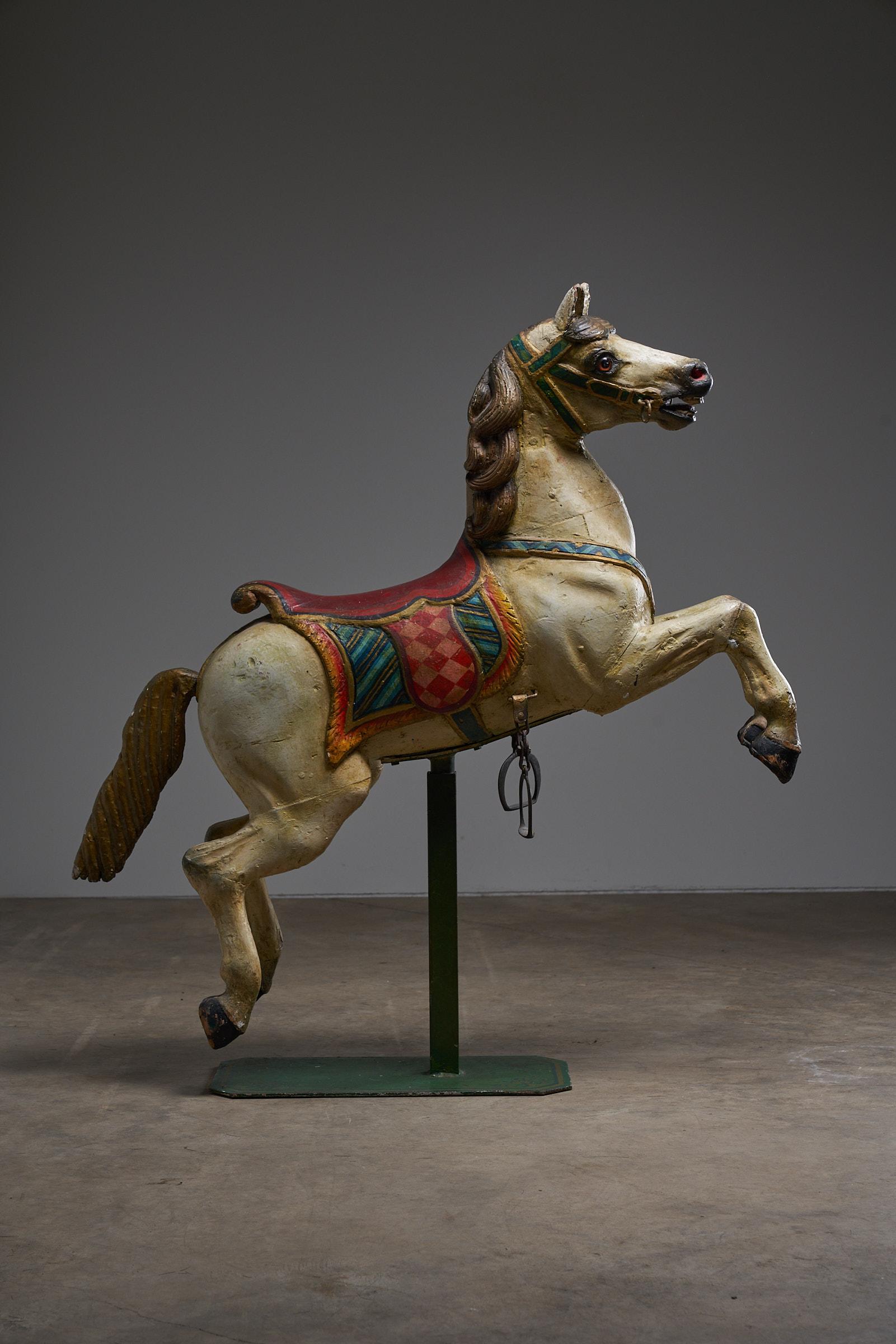 This antique hand-painted wooden carousel horse is a beautiful piece of fairground history, expertly crafted with attention to detail. The multicolored design features a classic saddle and vibrant harness, capturing the charm and whimsy of vintage