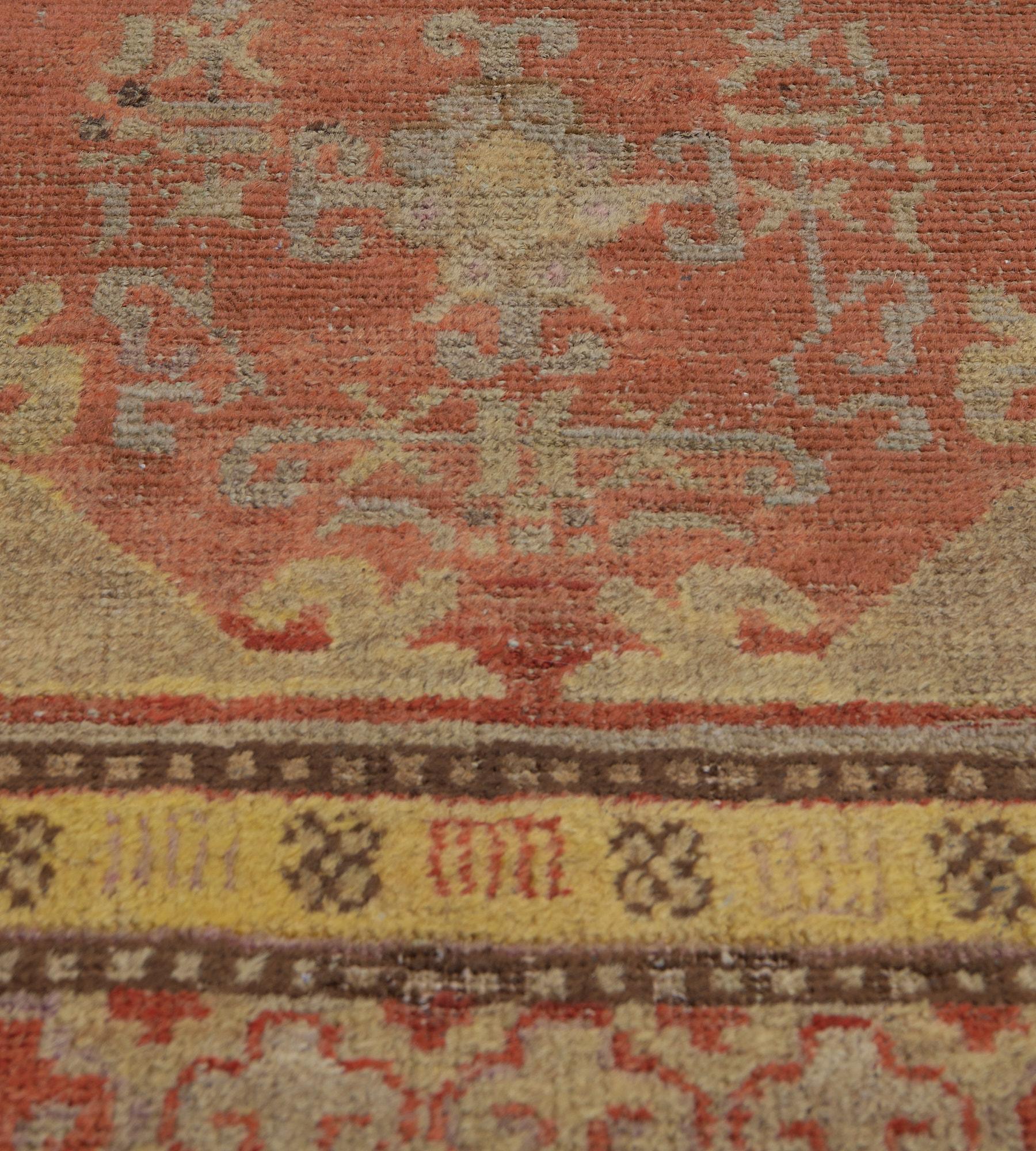 Cette ancienne coulisse Khotan, datant d'environ 1900, présente un champ rouge brique avec divers motifs crochetés autour d'une colonne centrale de cinq losanges, chacun avec une tête de fleur centrale entourée d'une délicate bande de motifs floraux