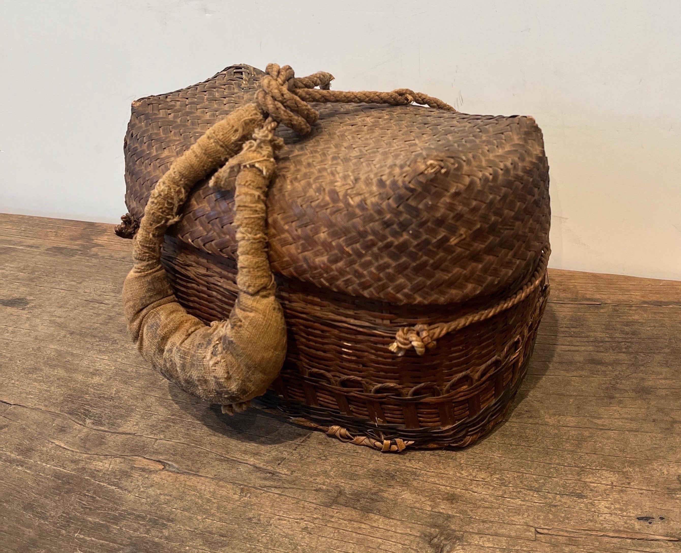 A beautifully handwoven provincial Chinese basket, with a very unusual thick cloth handle.  The texture of this piece is palpable.  It will pop from any shelf or table on which it is placed.  The large, striking cloth handle, which is central to the