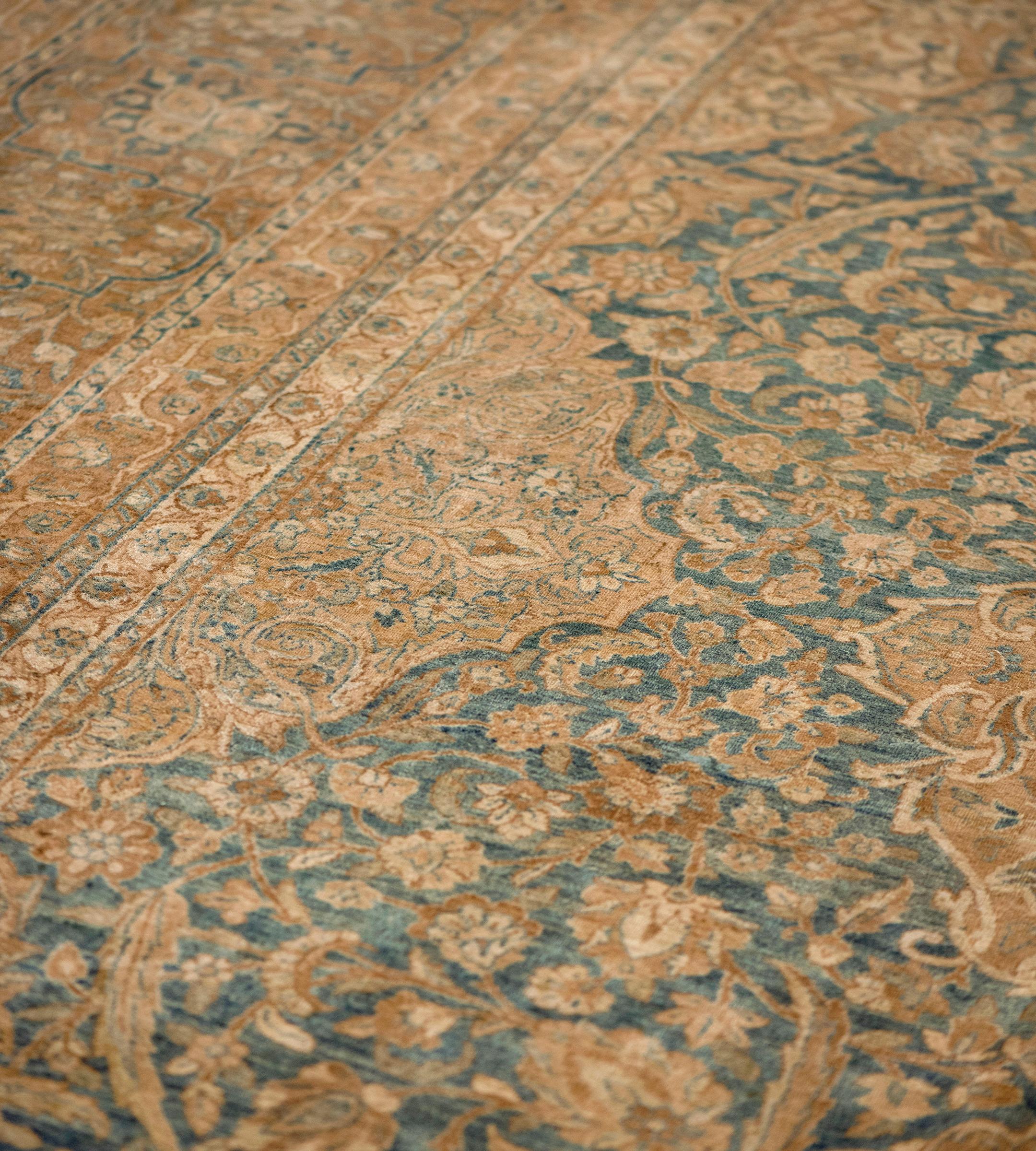 Ce tapis ancien, circa 1900, a un champ bleu marine nuancé avec une dense vigne florale et feuillue autour de trois colonnes de cartouches floraux et de palmettes marron-renard et ivoire, chacune avec une tête de fleur centrale émettant une vigne